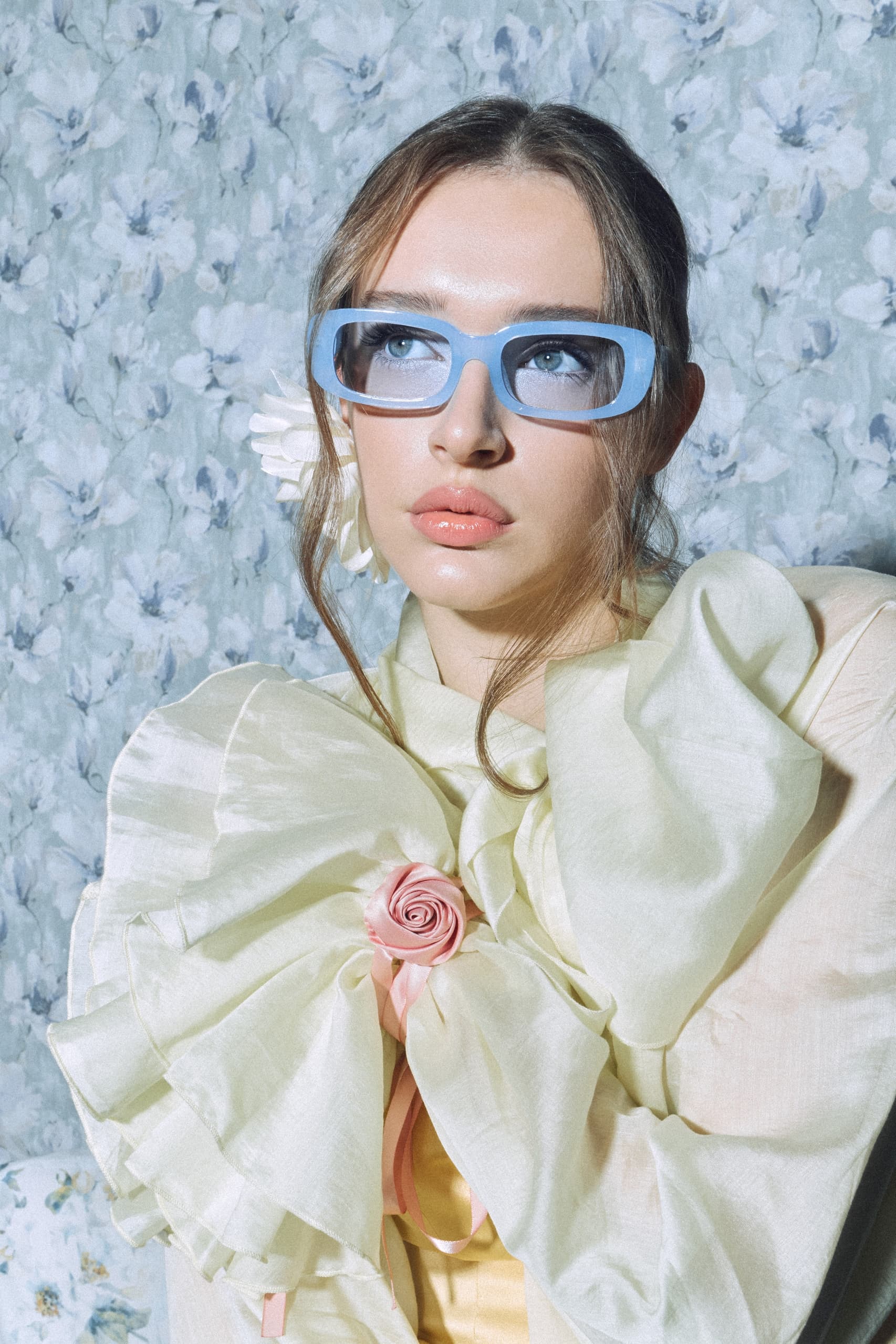 Fashion portrait with blue glasses and floral background.