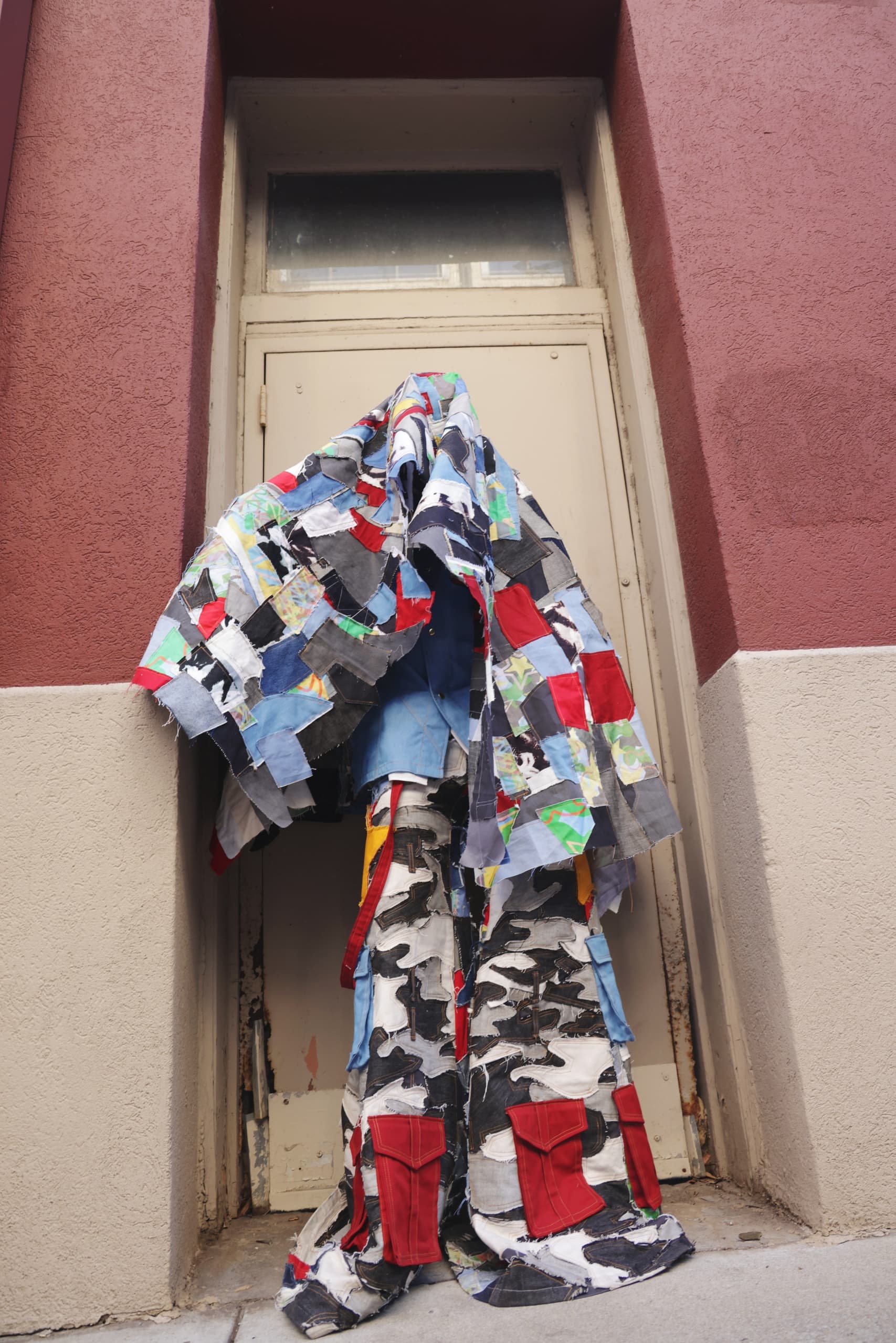 Patchwork quilt draped over doorway in urban setting.
