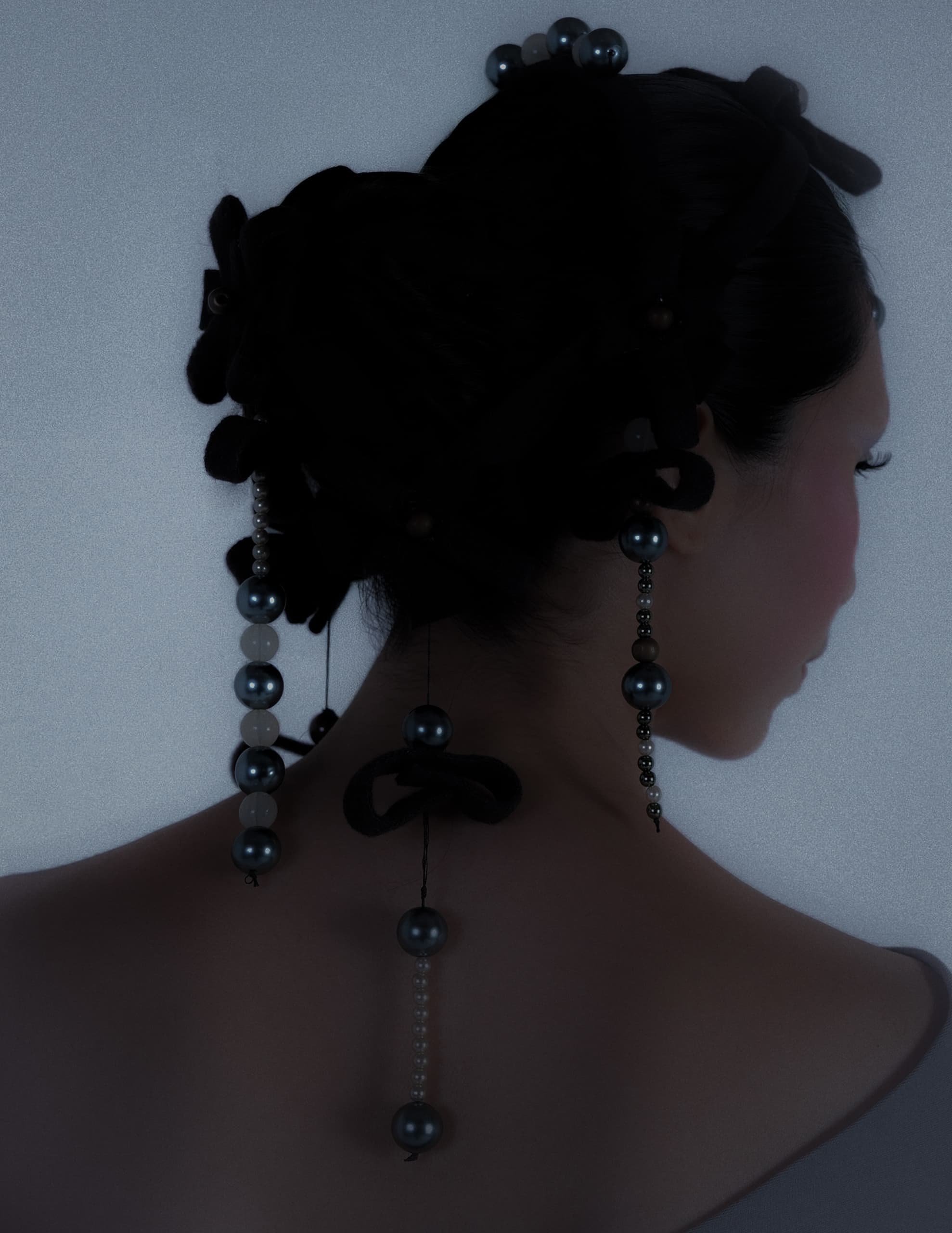 Elegant updo with pearl accessories on a softly lit background.
