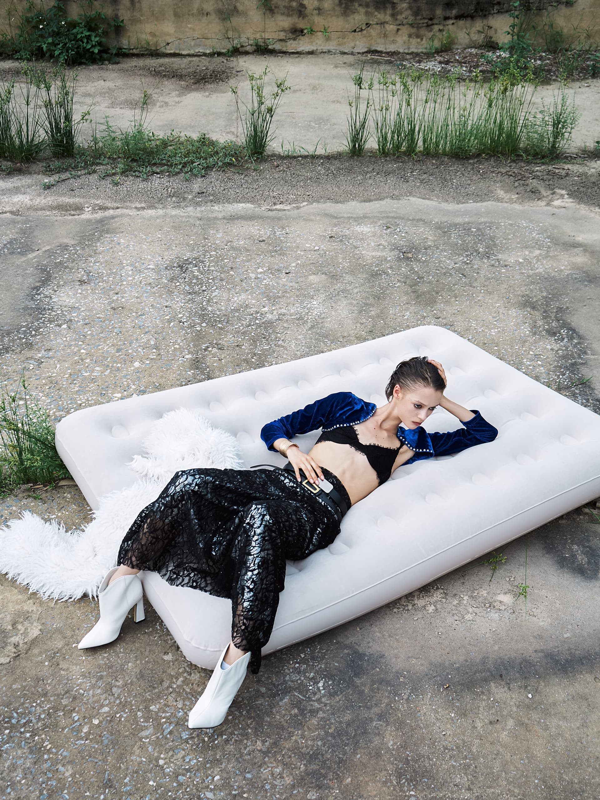Person lounging stylishly on an outdoor air mattress in trendy fashion attire.