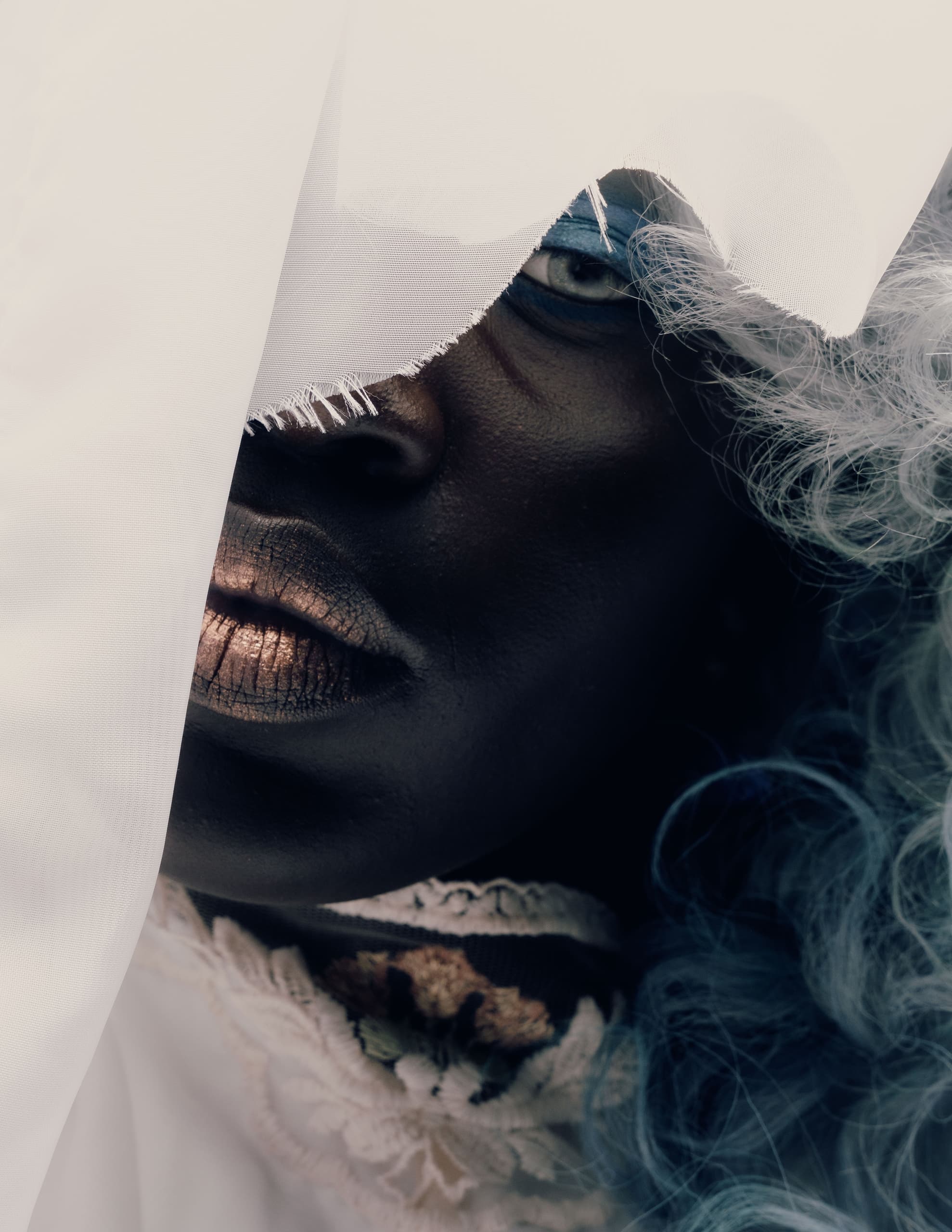 Mysterious portrait with fabric and dramatic lighting highlights face and texture.