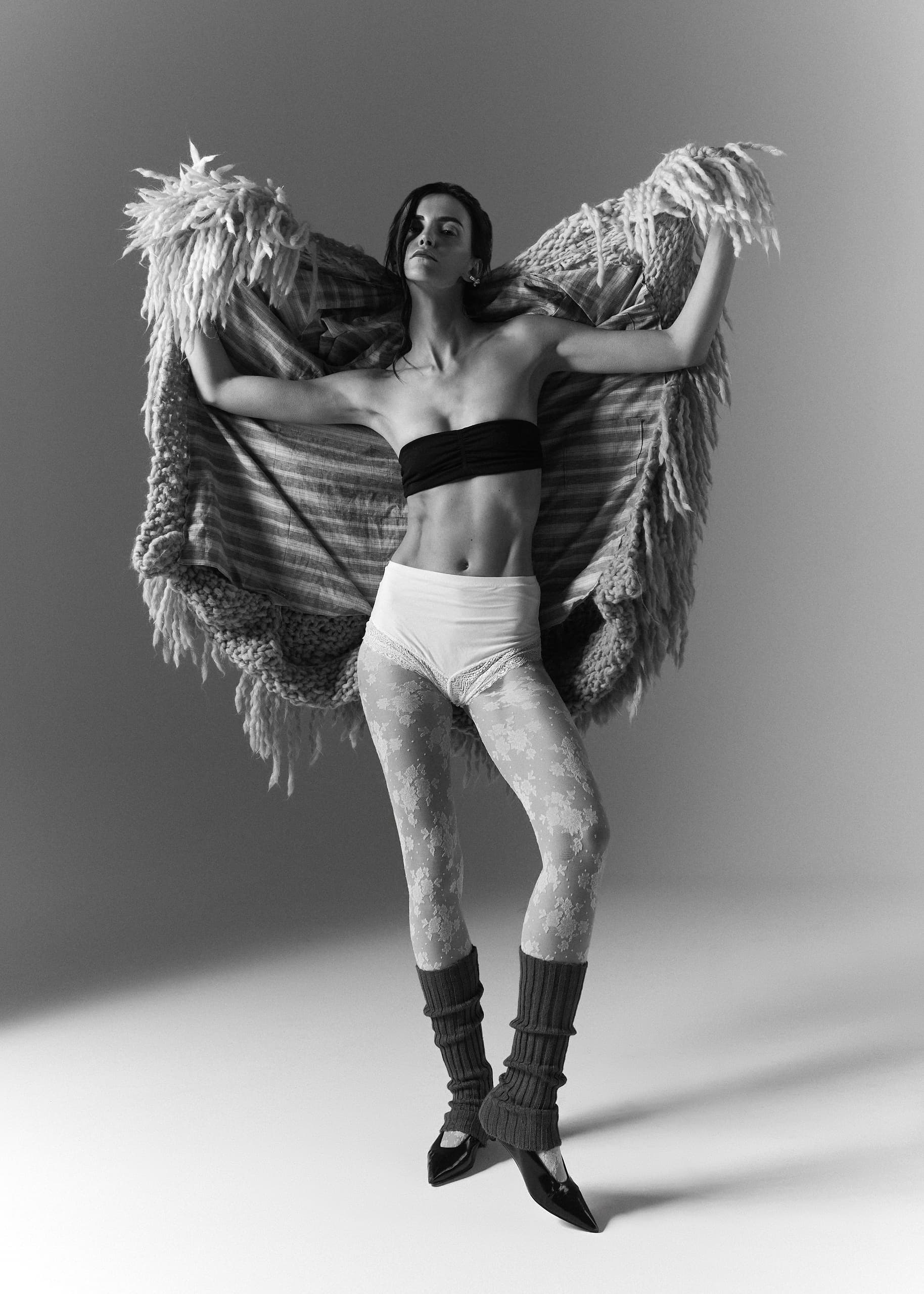 Fashion model posing with a textured shawl in a dramatic black and white photo.