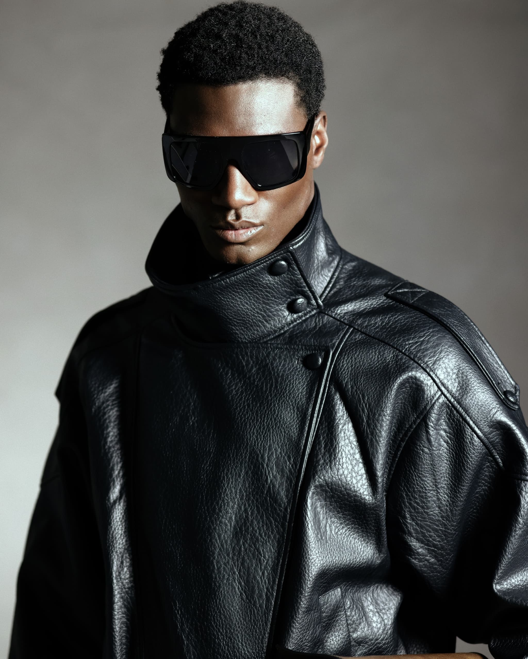Man in black leather jacket and sunglasses, fashion portrait with dramatic lighting.