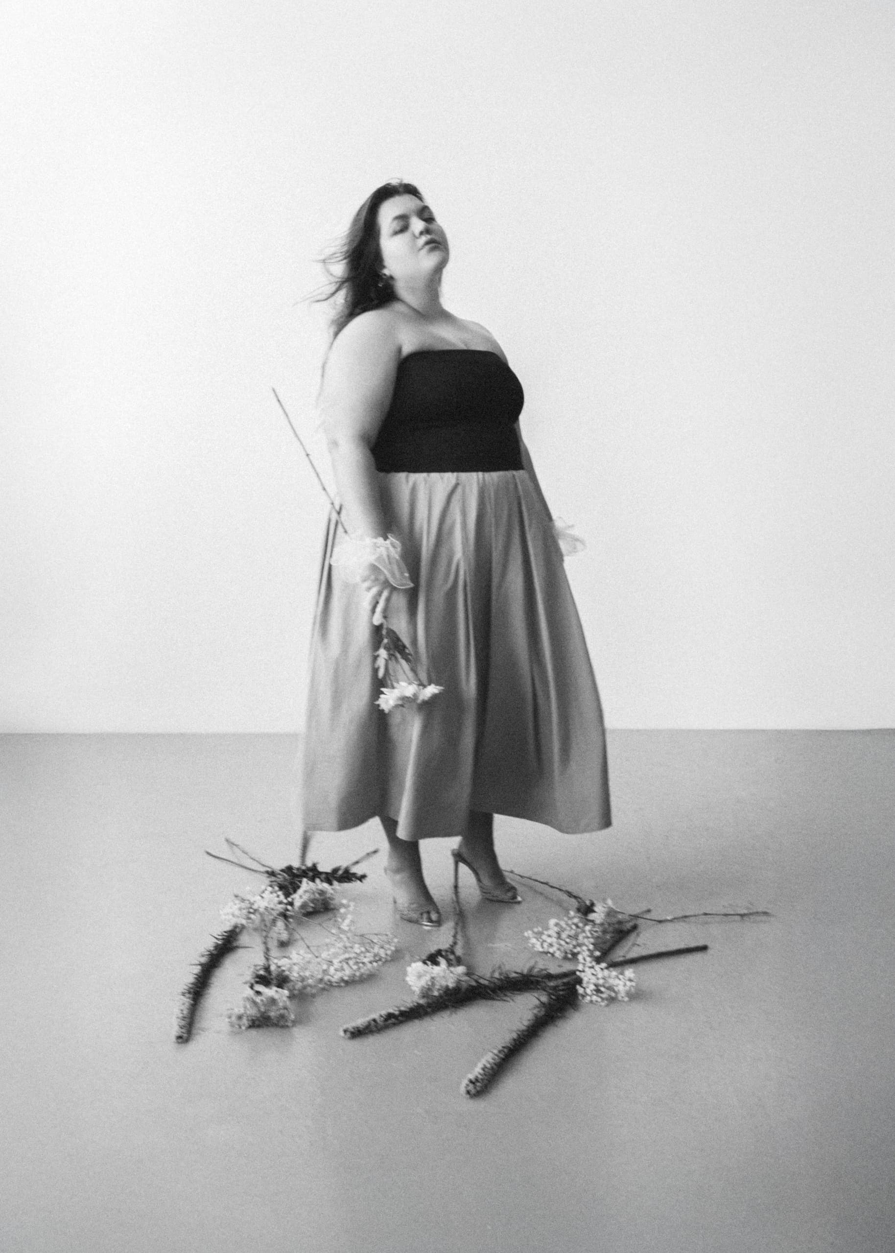 Woman in elegant dress holding flowers, black and white photography.