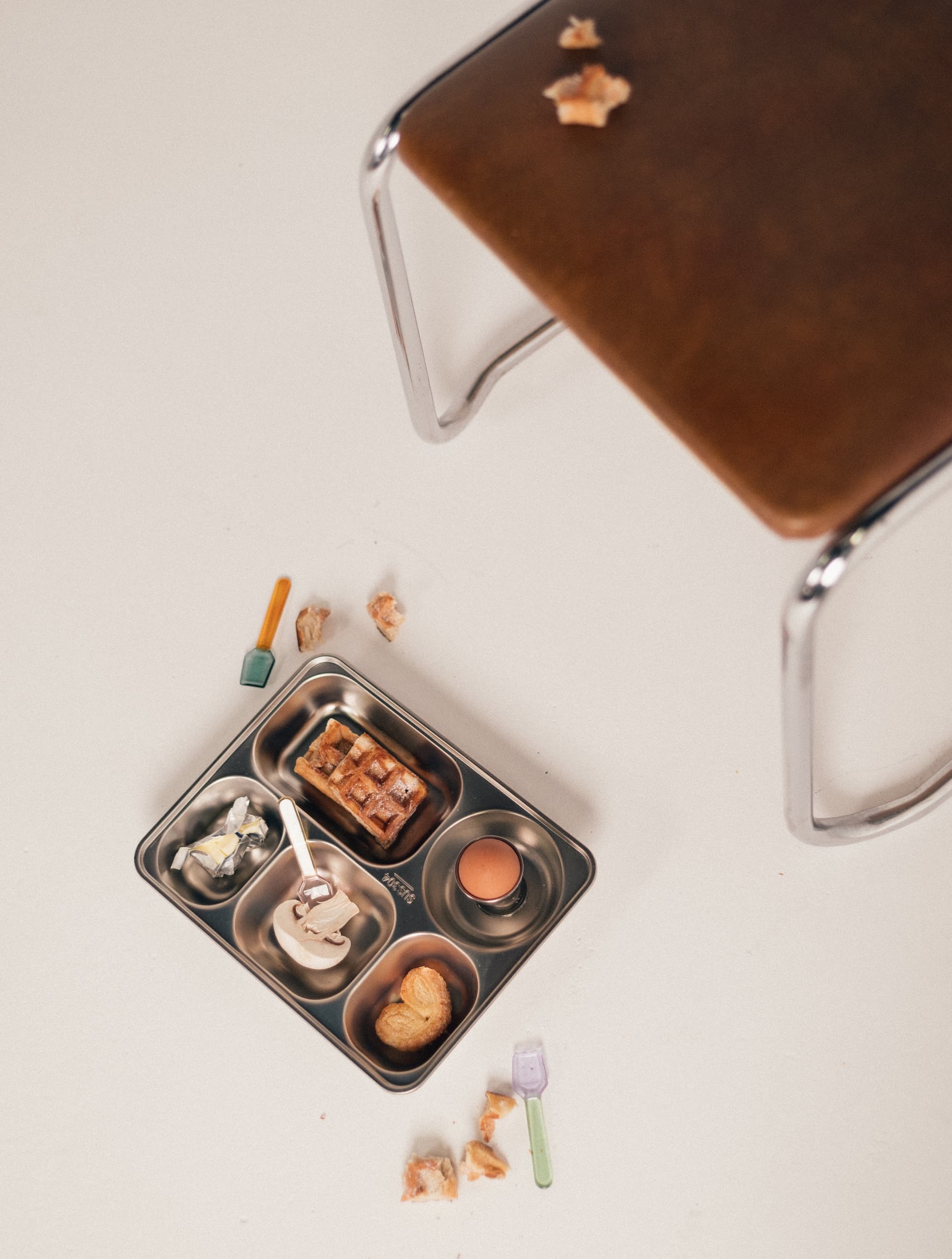 Metal tray with breakfast items on light table, viewed from above.