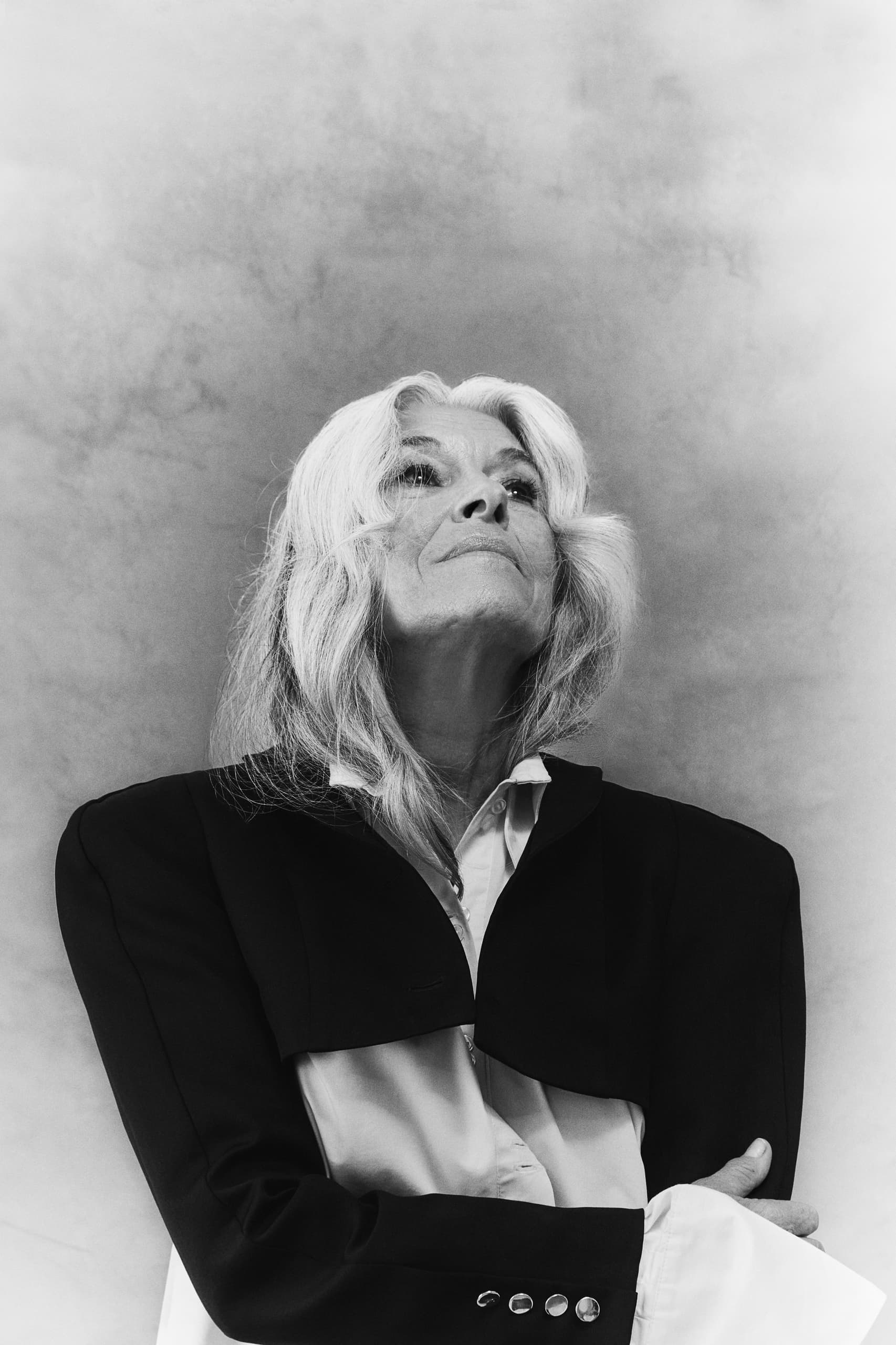 Elegant woman in black jacket gazes upward with confidence, monochrome portrait.