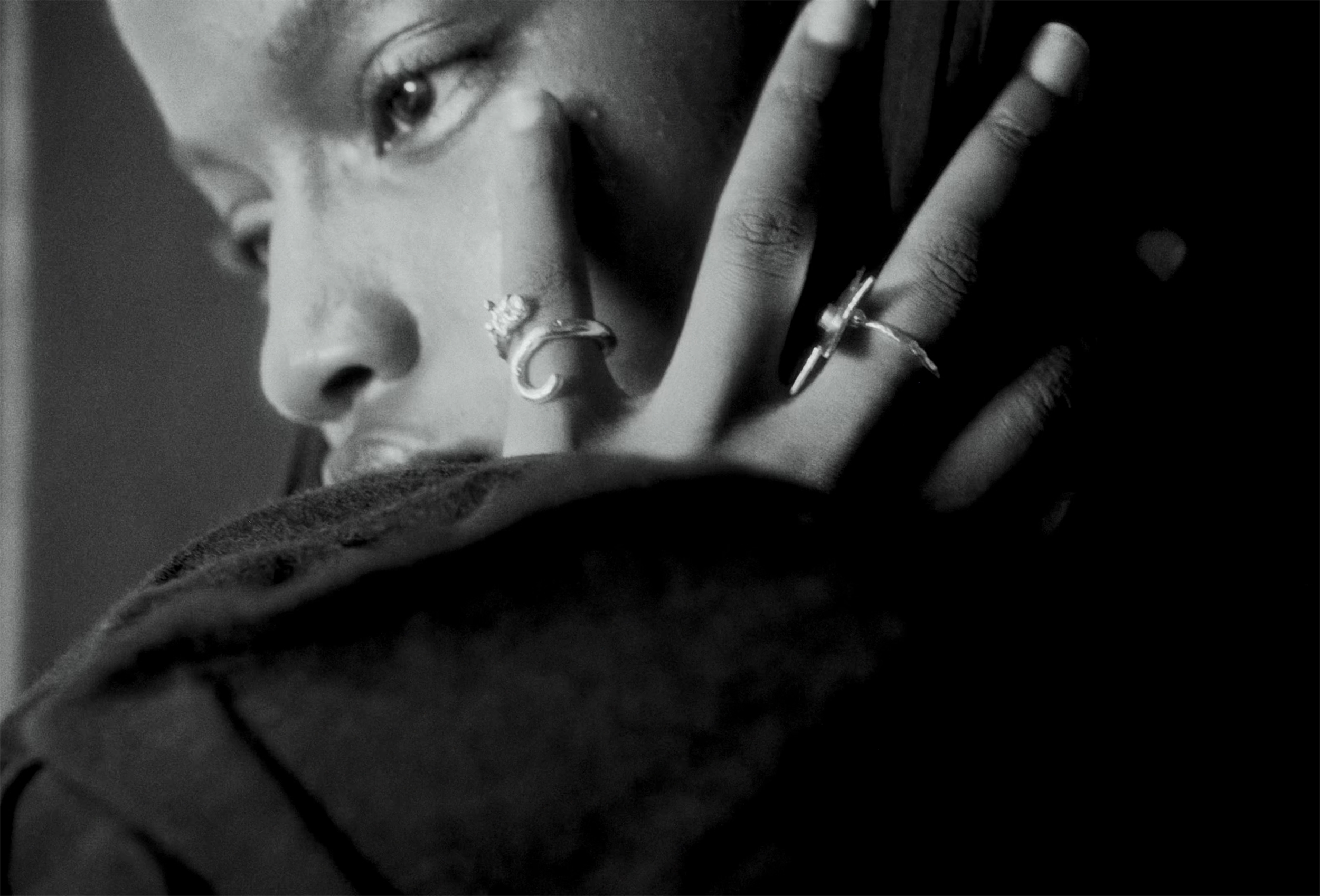 Close-up of a person wearing rings, in black and white.