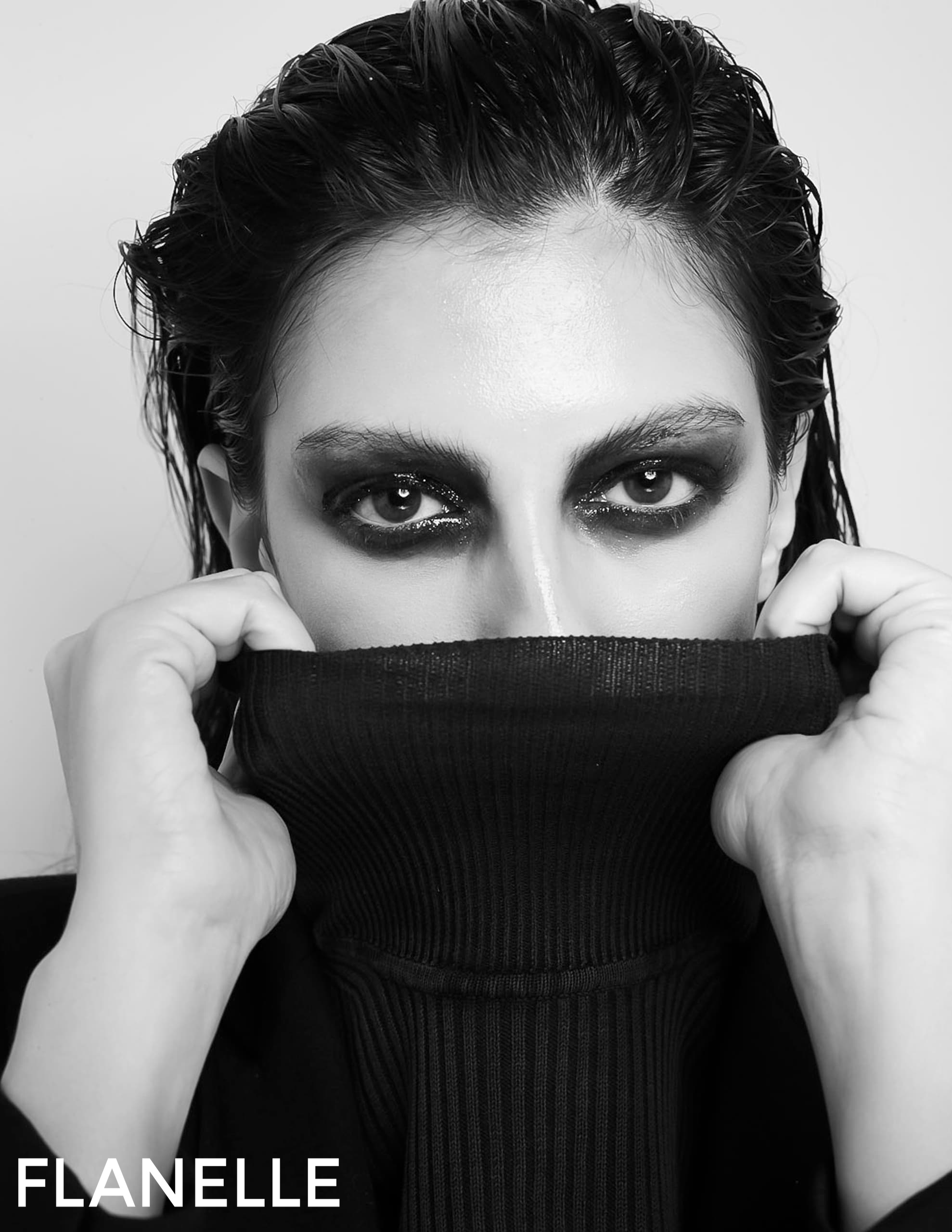 Edgy fashion portrait with bold eye makeup and black turtleneck sweater.