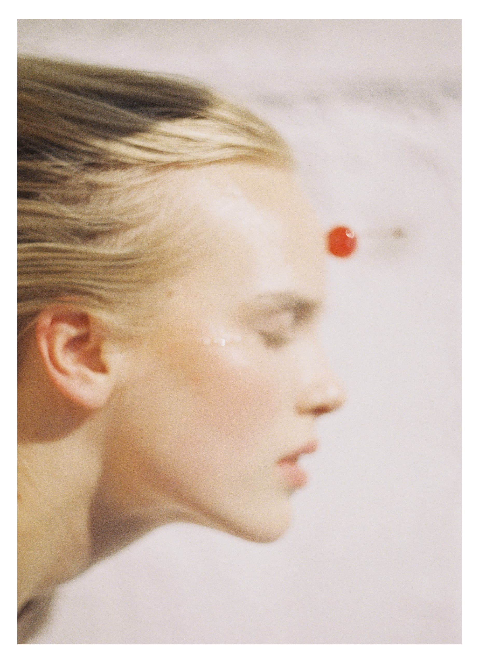 Blurred profile of a person with neutral background and a red cherry accent.