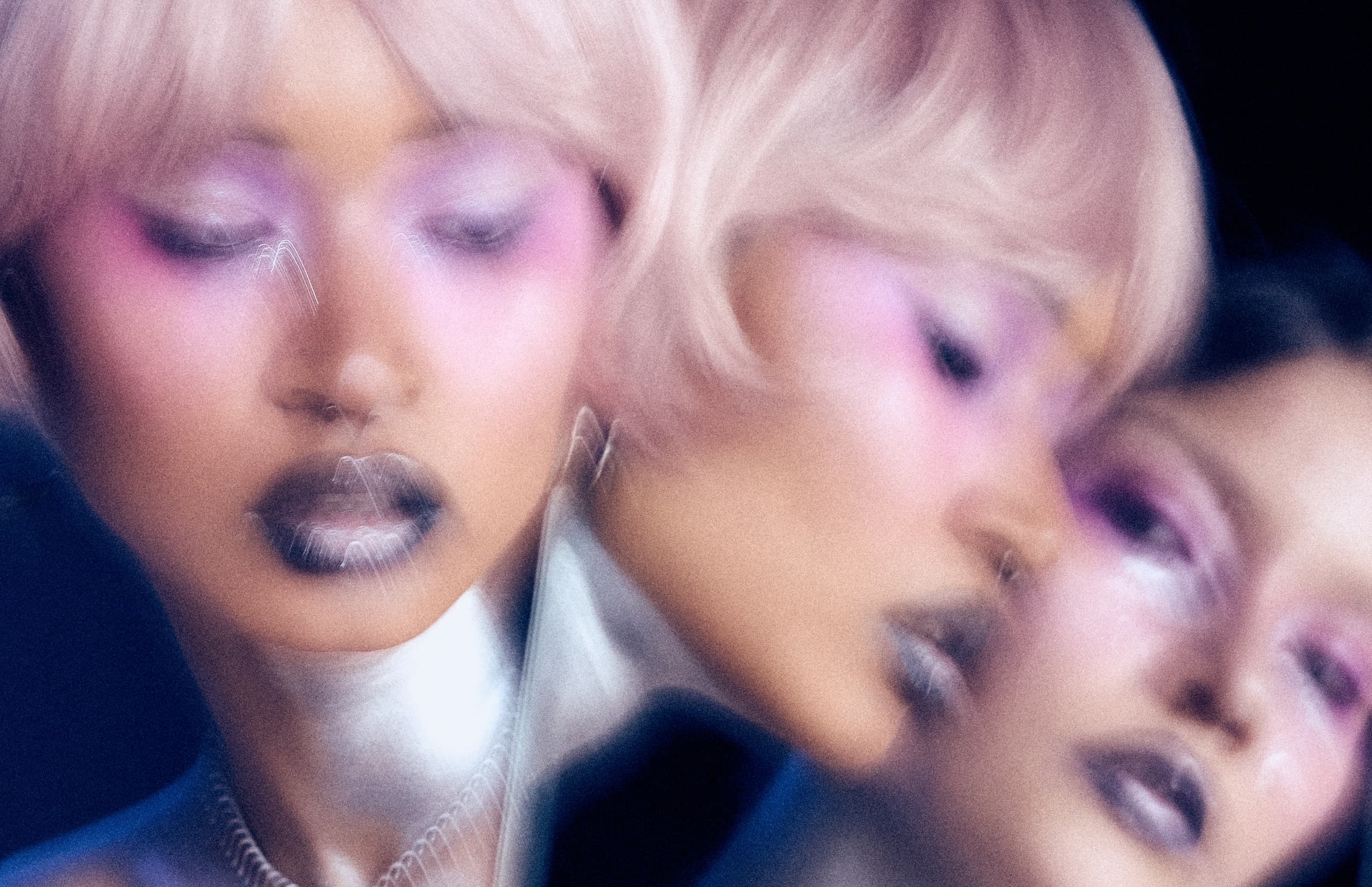 Abstract portrait with motion blur and vibrant pink and purple makeup.