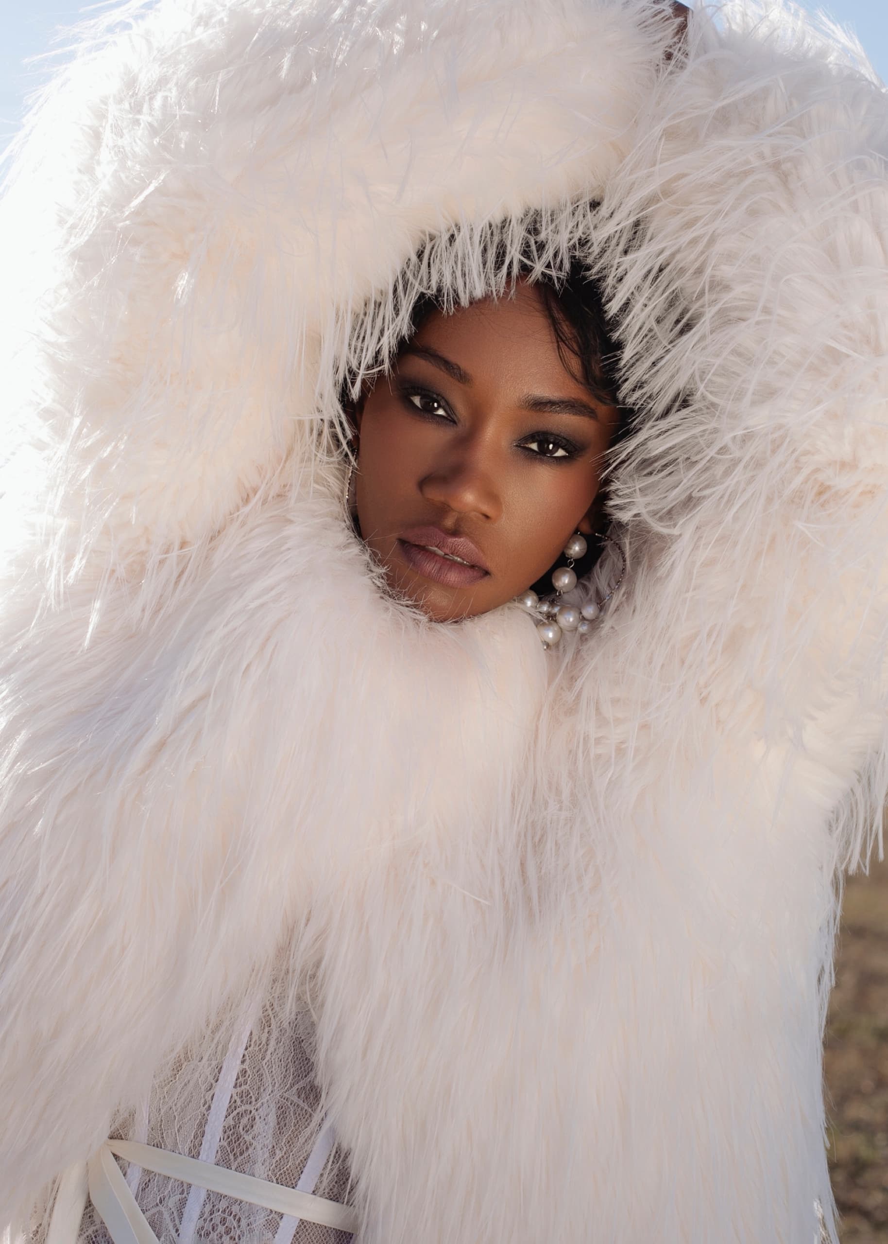 Model in luxurious white fur coat on a bright day.
