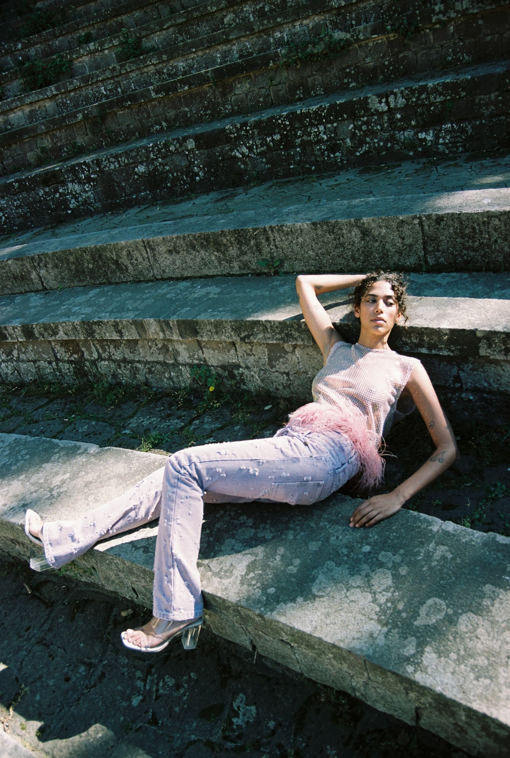 Fashion model posing on stone steps in stylish outfit, outdoors photo shoot.