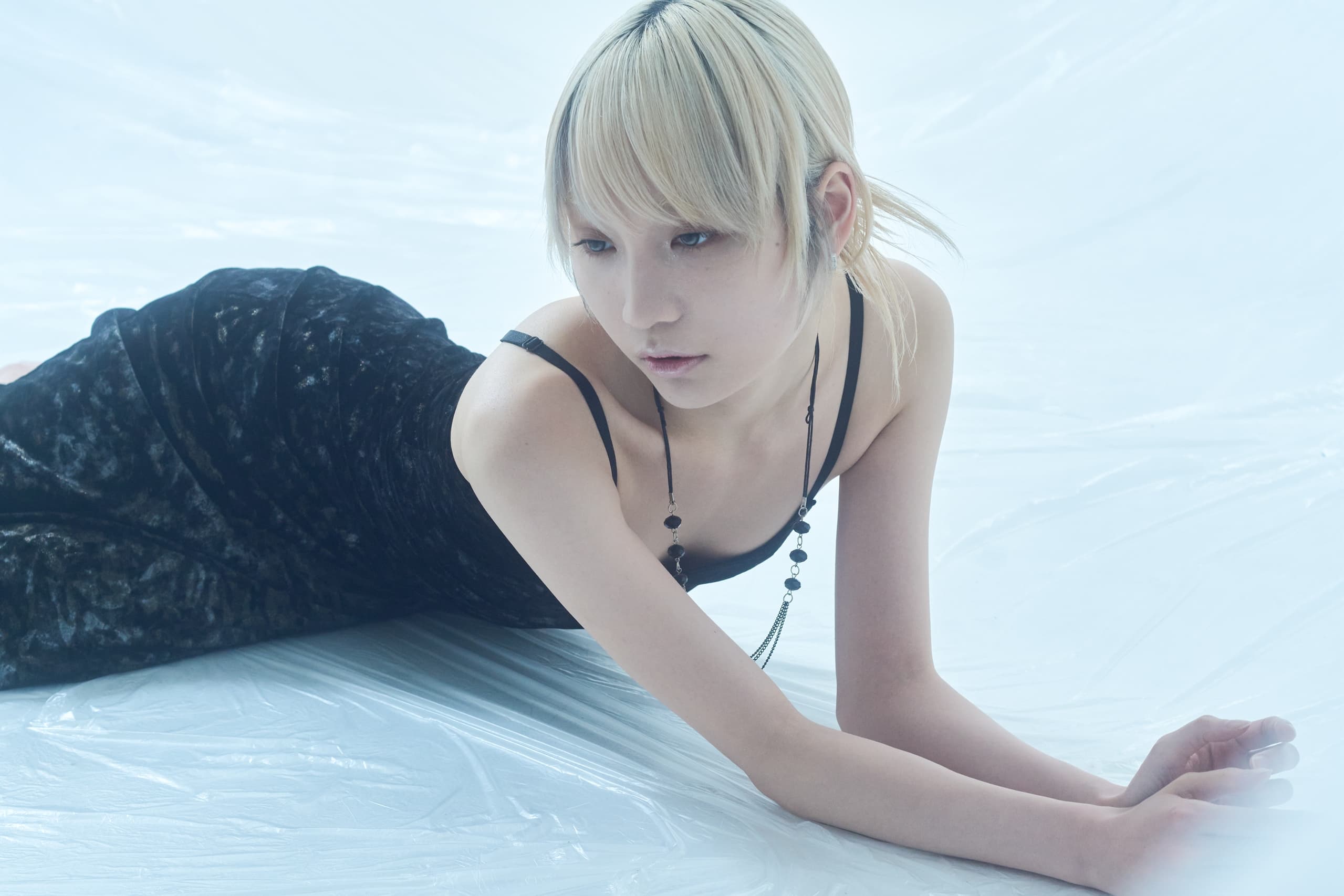 Person in black dress on white background, elegant and serene pose.