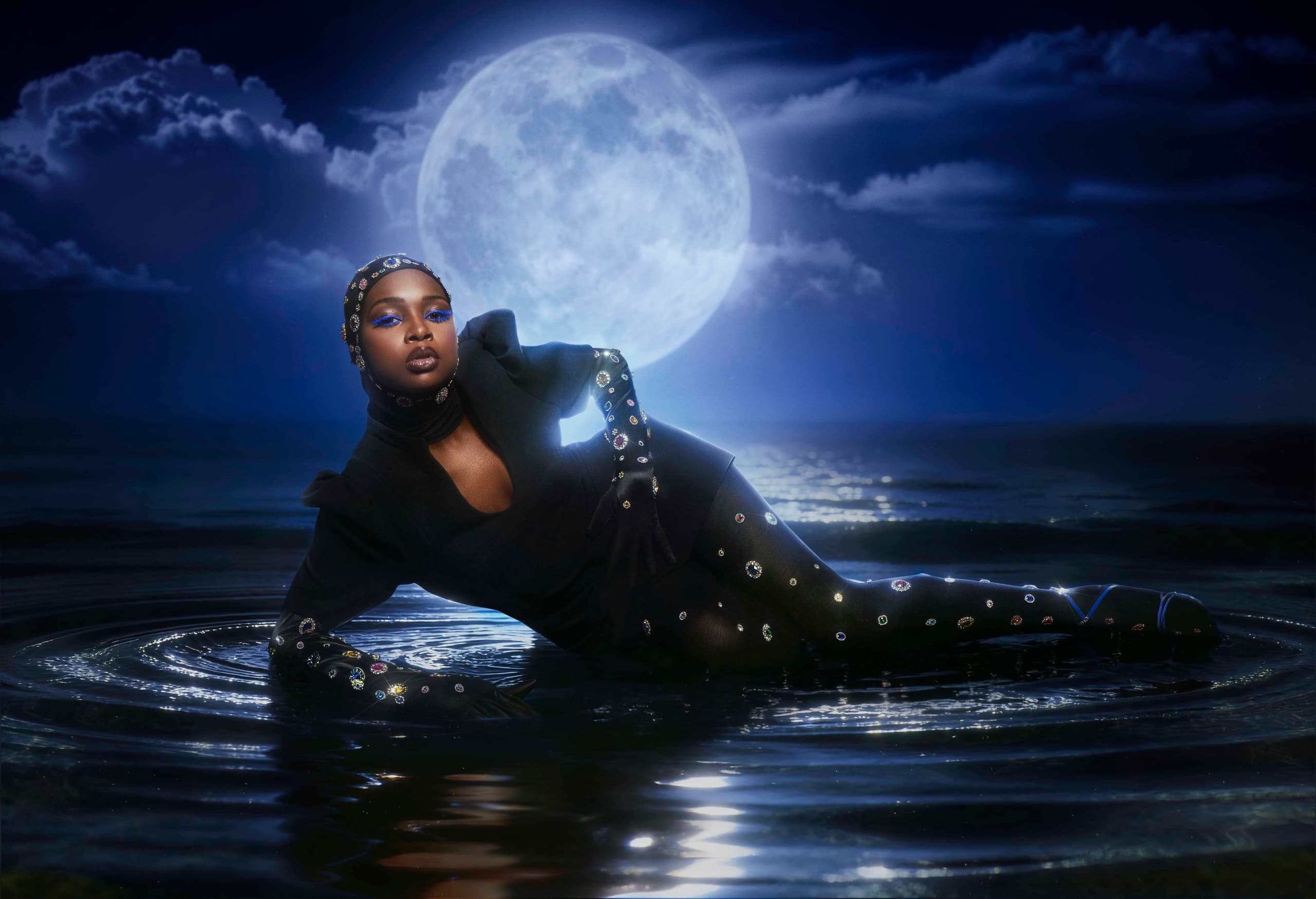 Fashion model posing in moonlit water, wearing embellished outfit. Enchanting night scene.