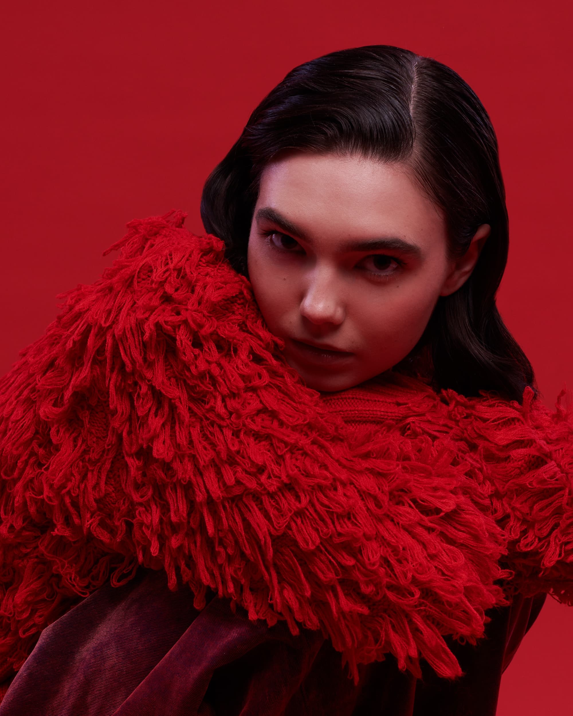 Person in a vibrant red-textured jacket against a matching red background.