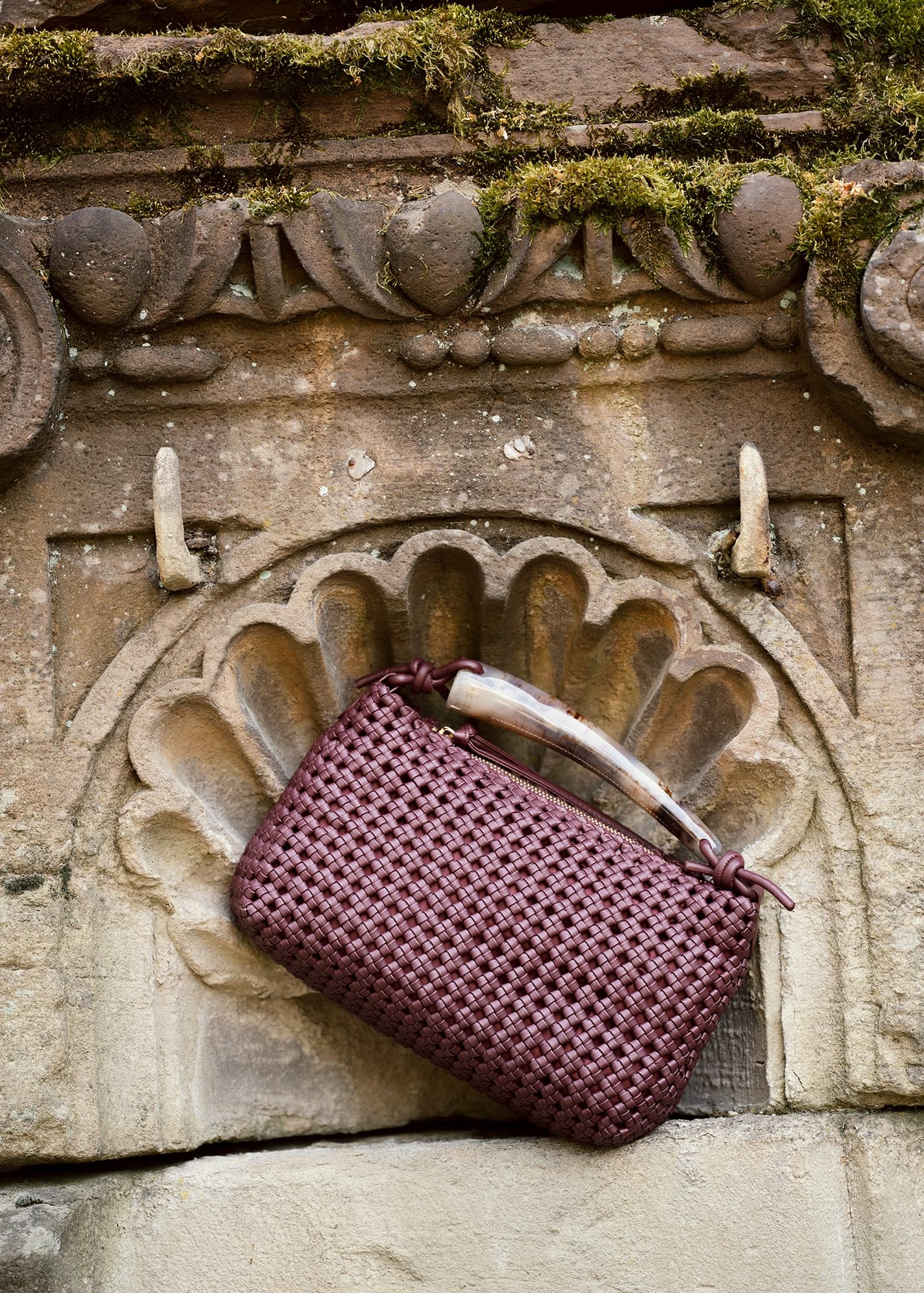 Vintage woven handbag on rustic stone background.