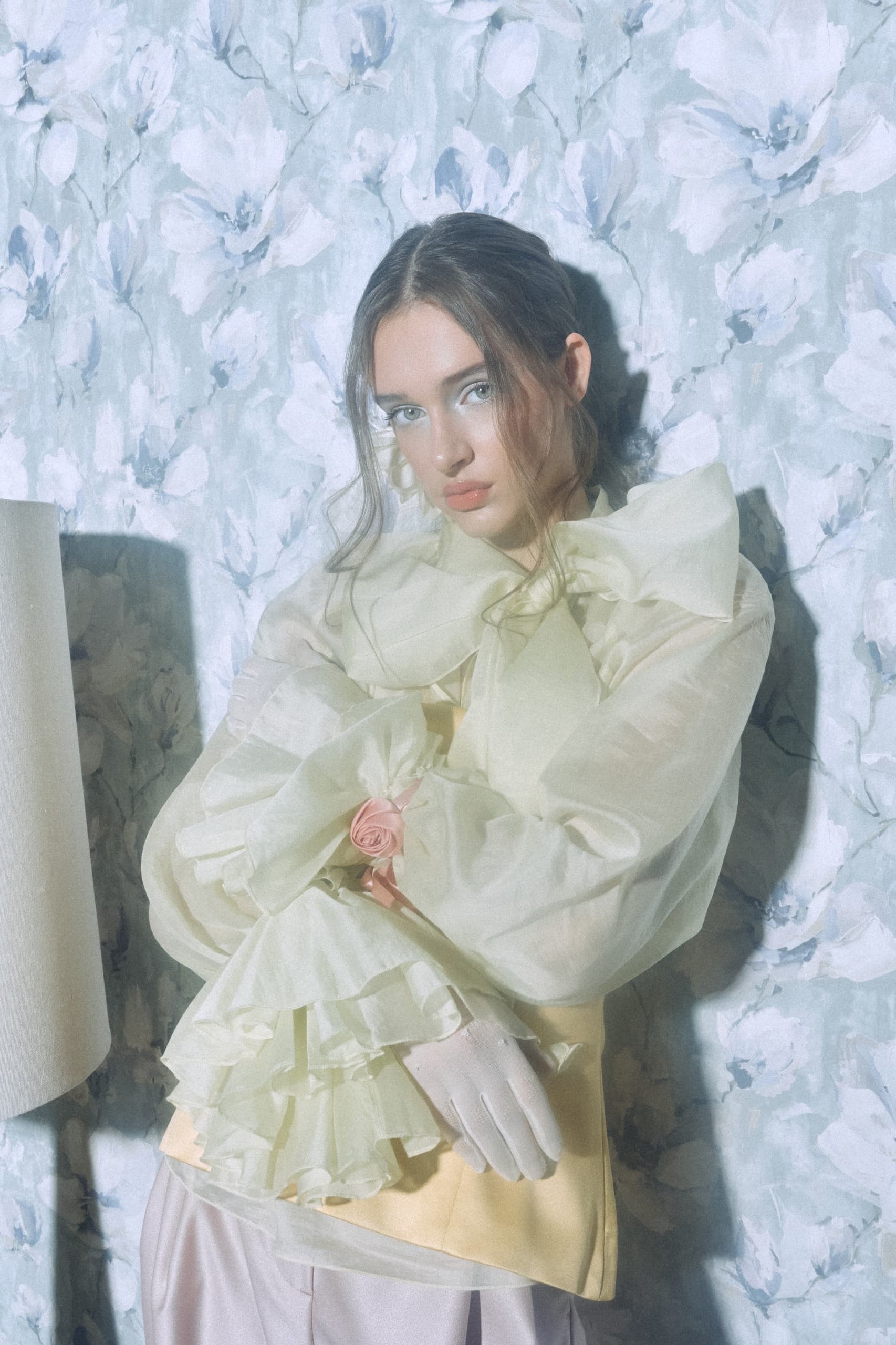 Woman in vintage floral outfit against a floral wallpaper background.