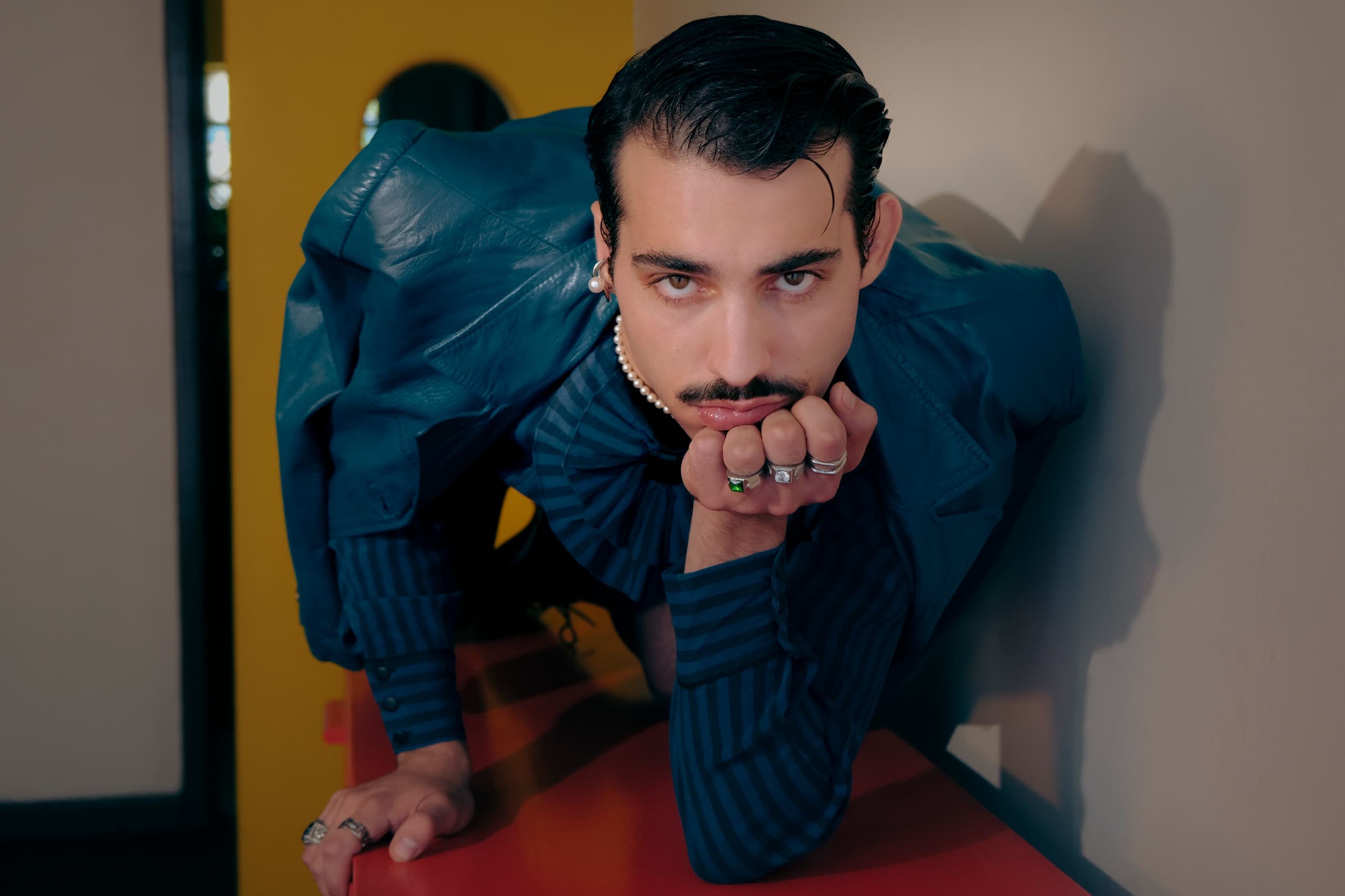 Fashionable man in bold blue outfit striking a unique pose.