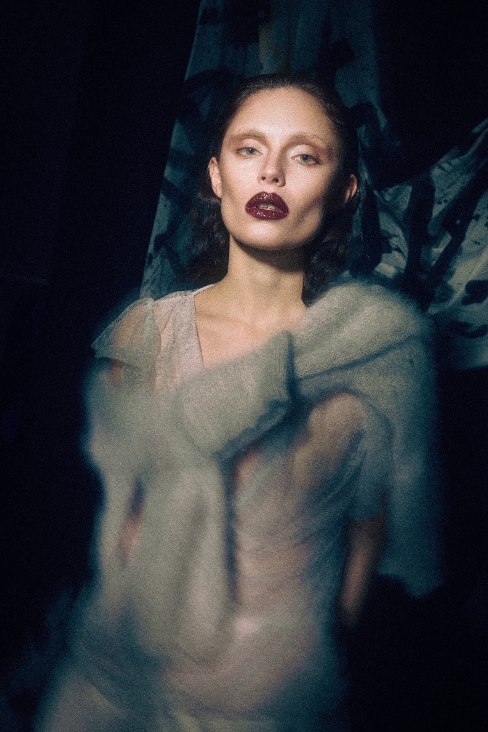 Moody portrait of a woman with dark lipstick and ethereal lighting.