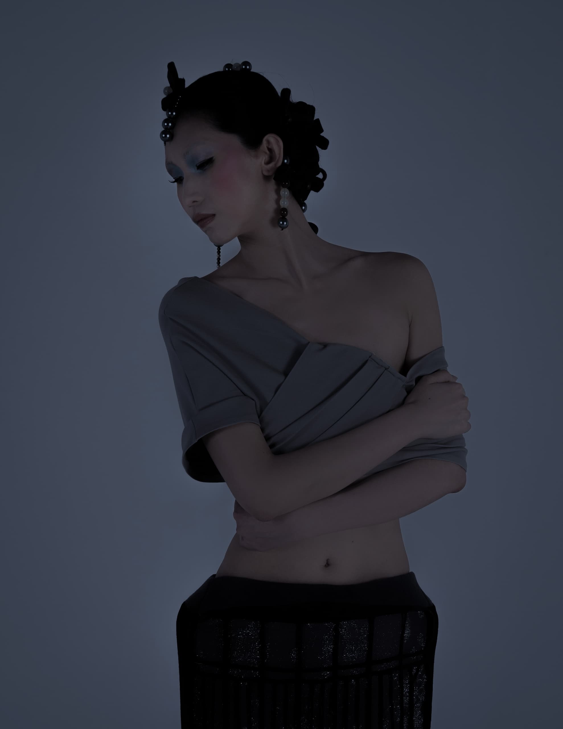 Elegant woman in fashion pose with stylish updo and off-shoulder outfit.