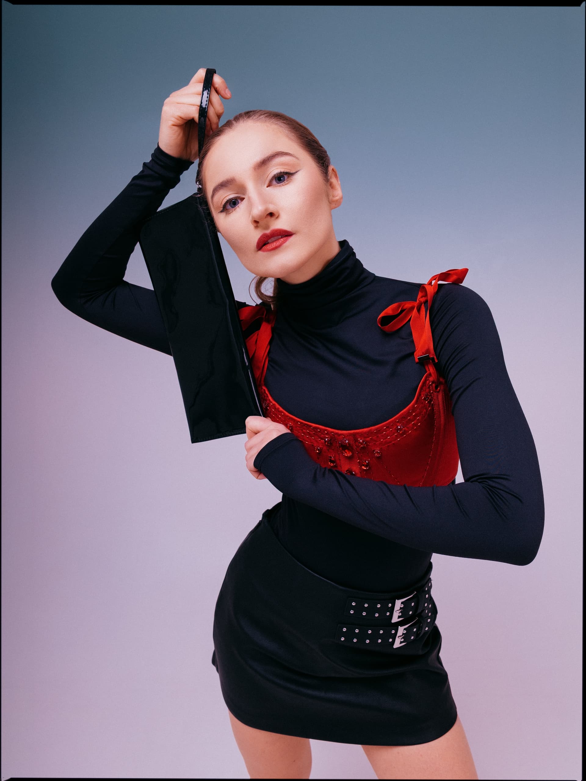 Fashionable woman in black and red outfit, holding a sleek black clutch.
