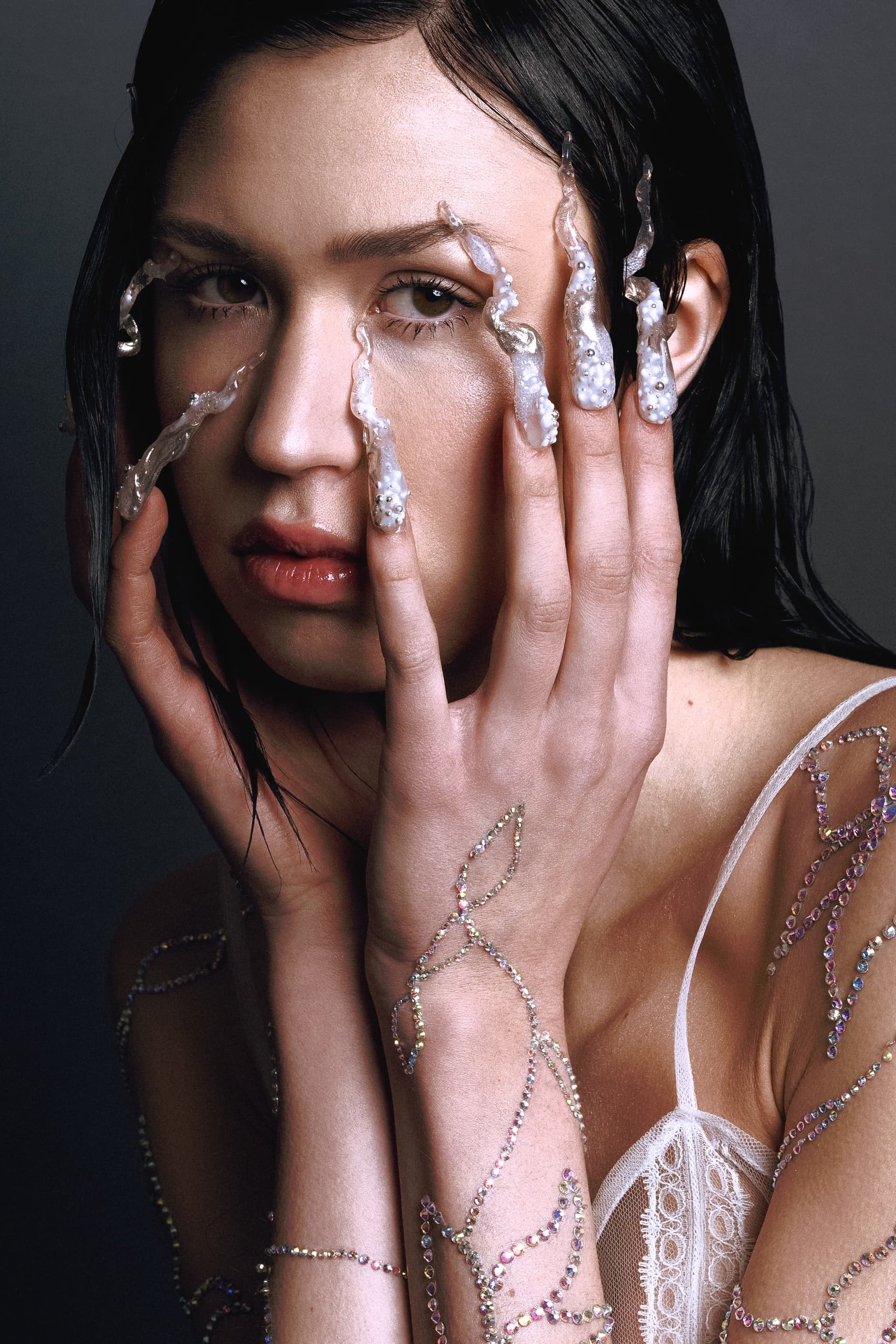 Creative nail art with ornate designs on woman's hands, close-up portrait.