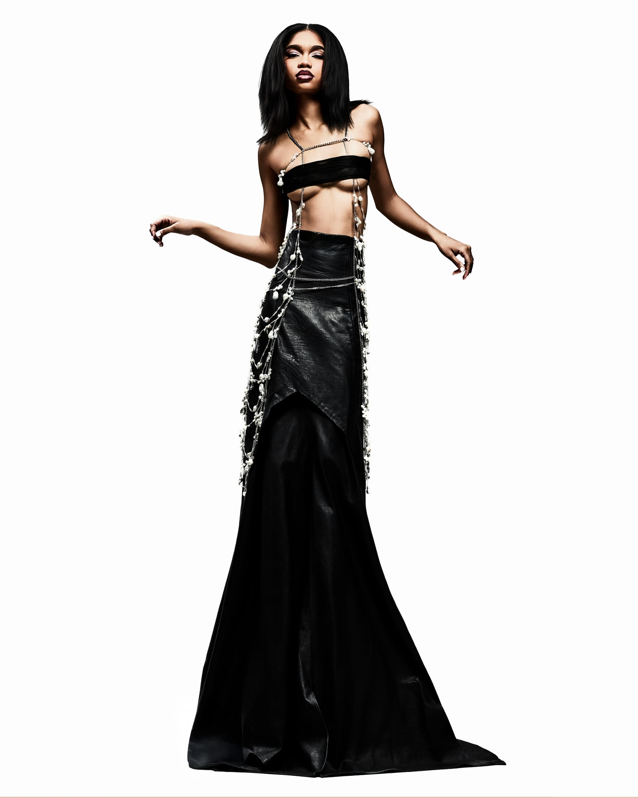 Model in avant-garde black gown with pearl adornments.