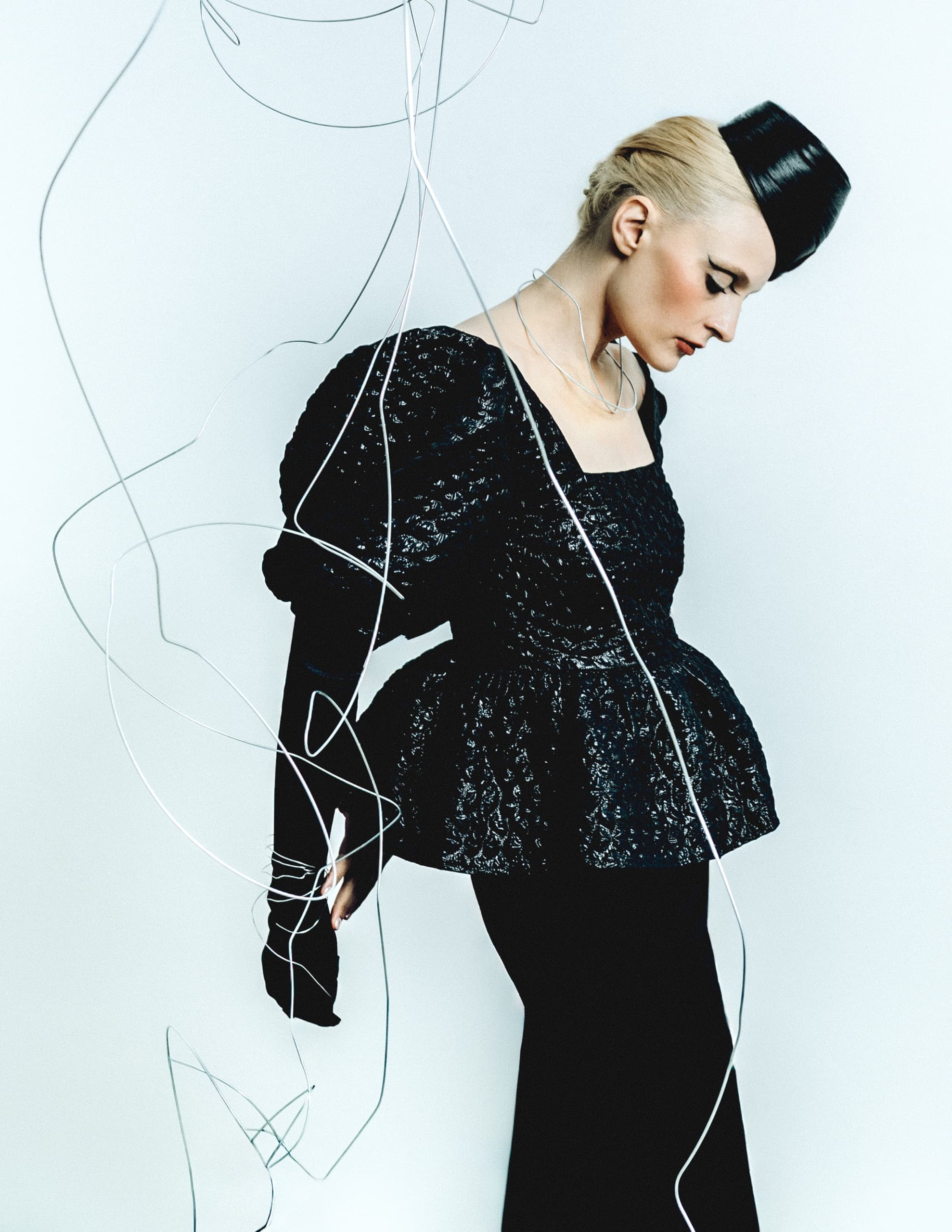Elegant fashion model in a black textured dress with artistic wires.