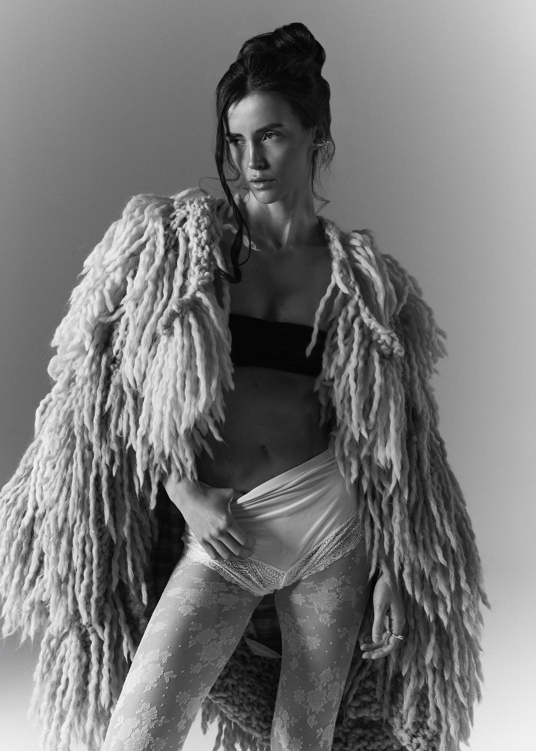 Fashionable woman in textured coat and patterned leggings, black and white photo.