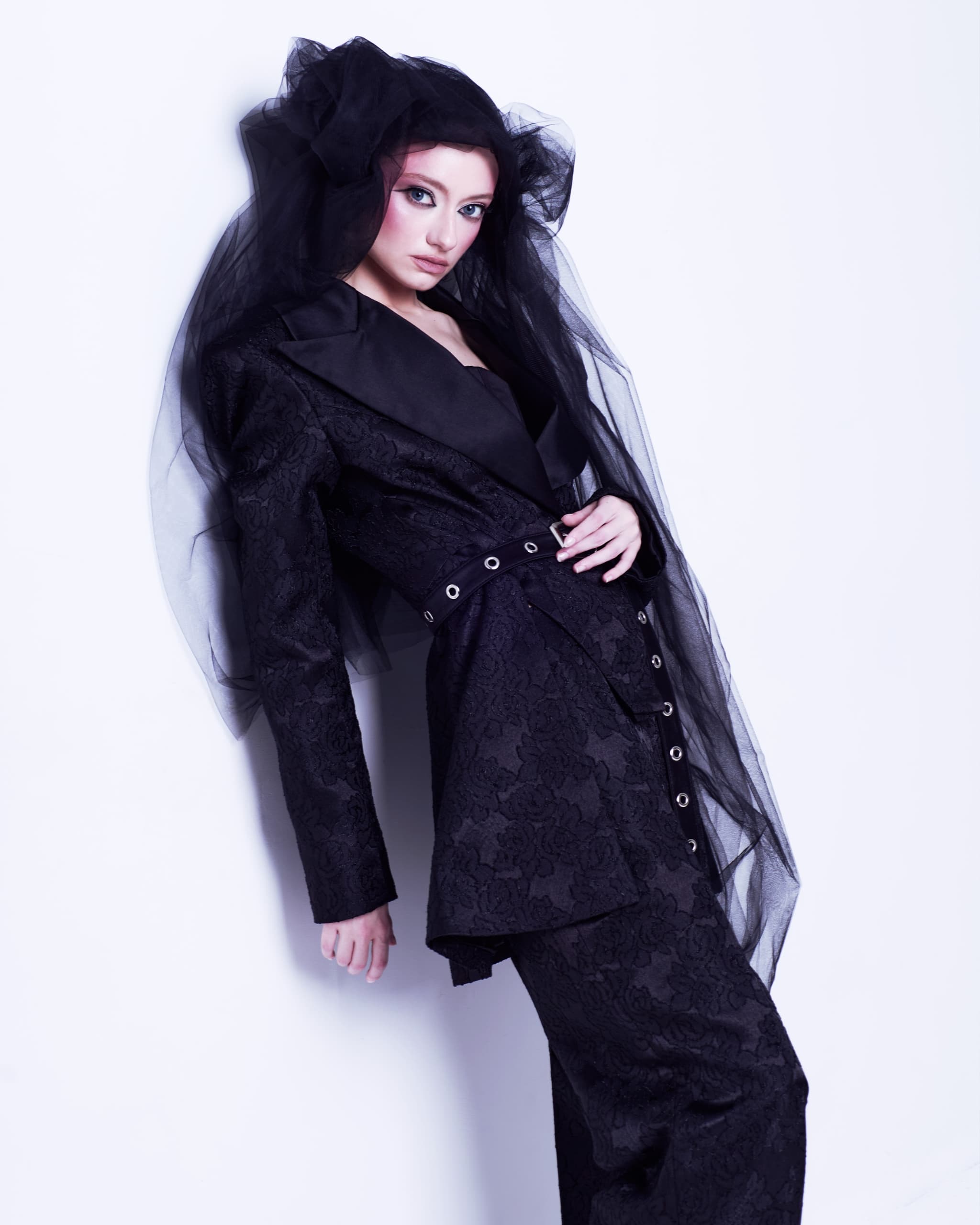 Elegant woman in black lace suit with veil, fashion portrait.