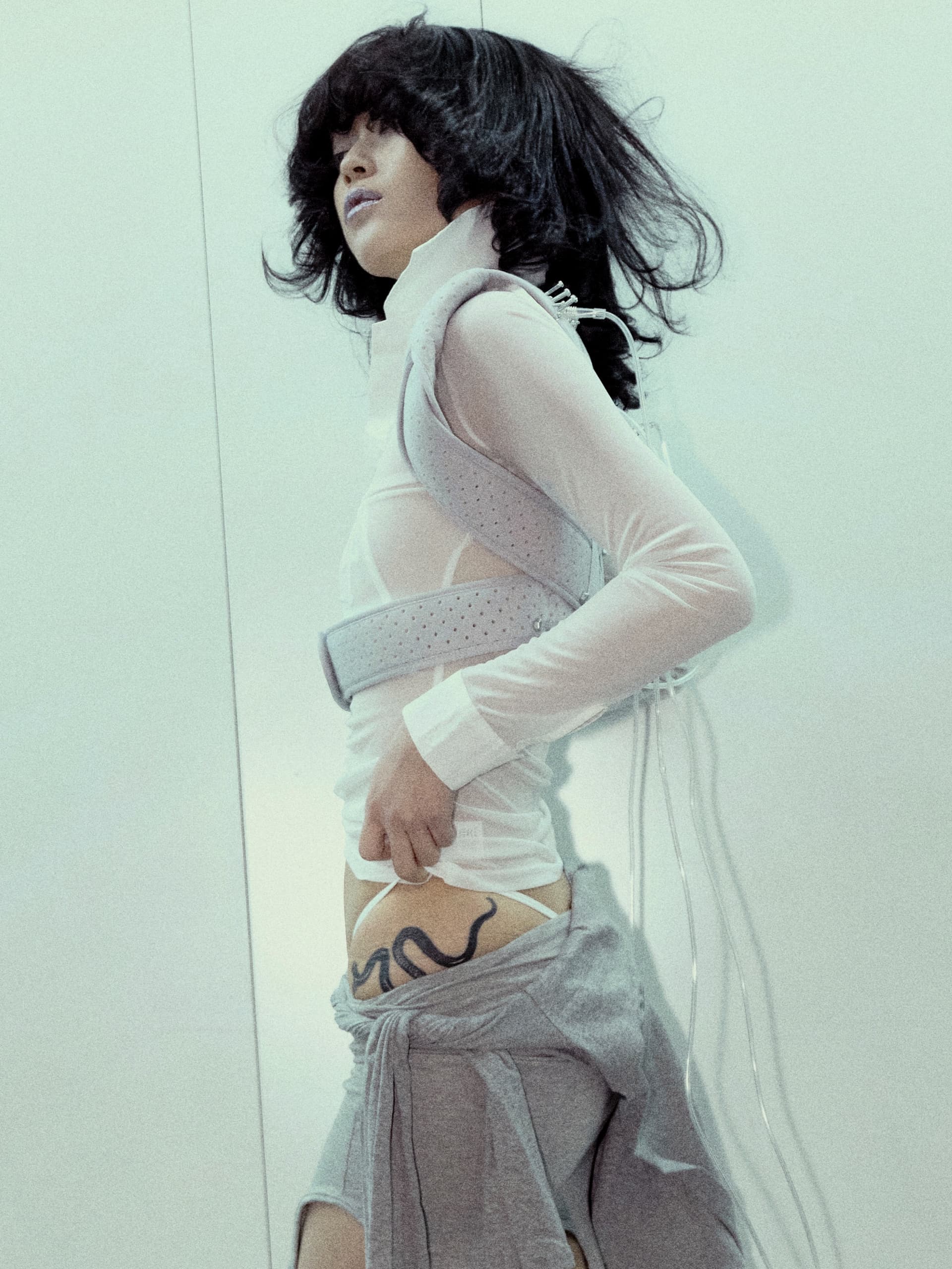 Fashion-forward individual with unique style and snake tattoo, striking dynamic pose.