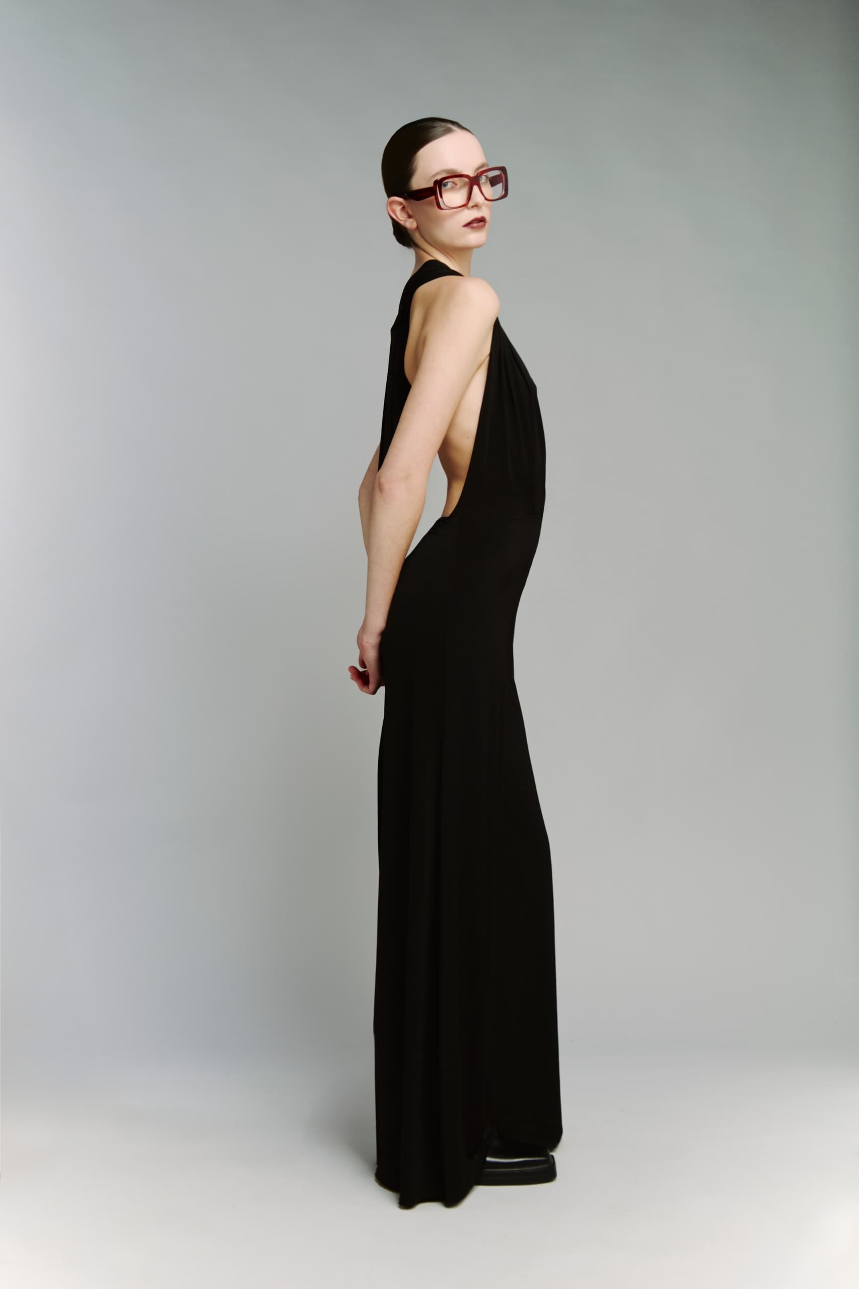 Elegant model in black dress with stylish large glasses.