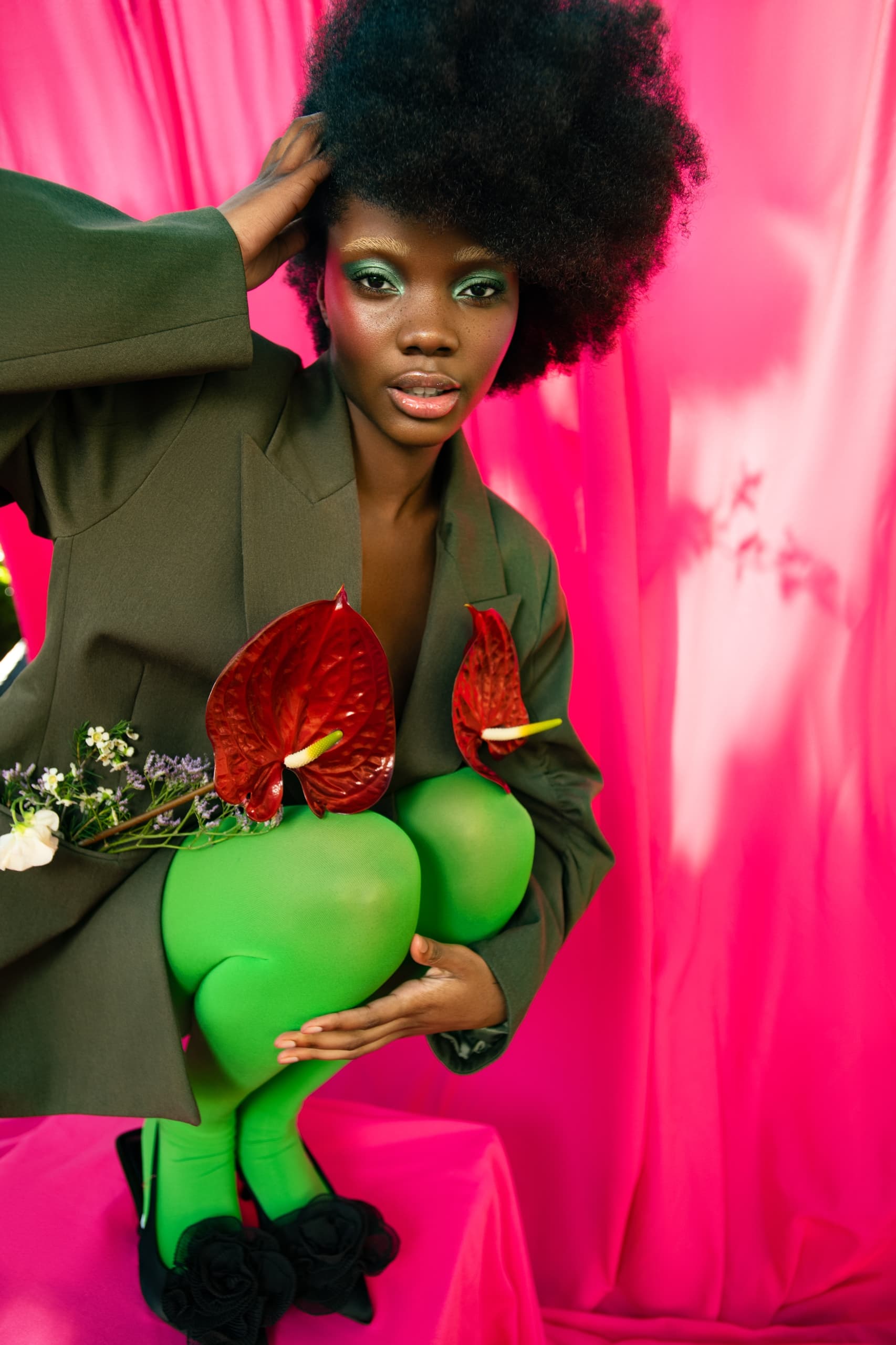 Creative fashion with bright colors, floral details, and bold makeup against pink backdrop.