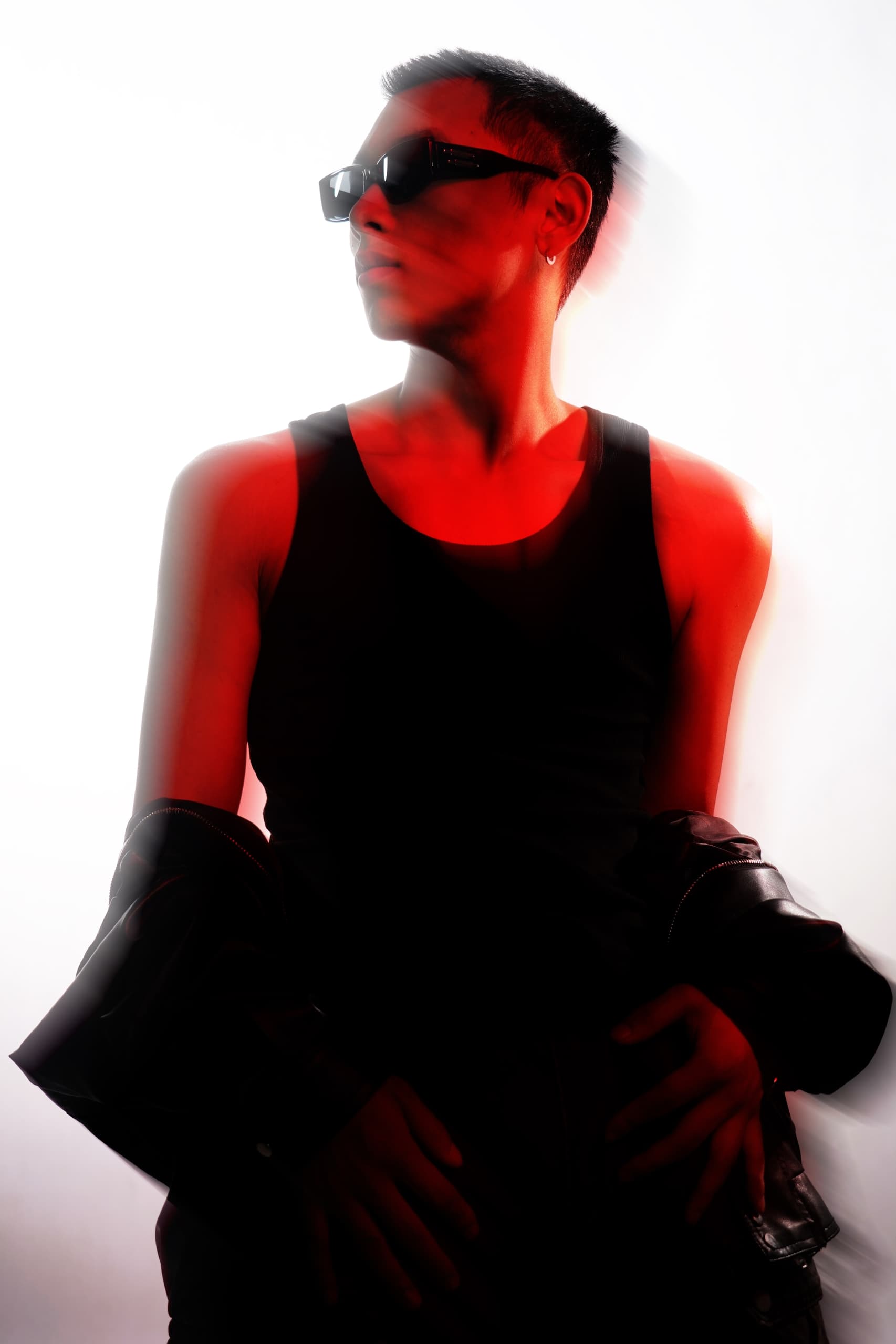 Stylish person in sunglasses and tank top under red lighting, with motion blur effect.