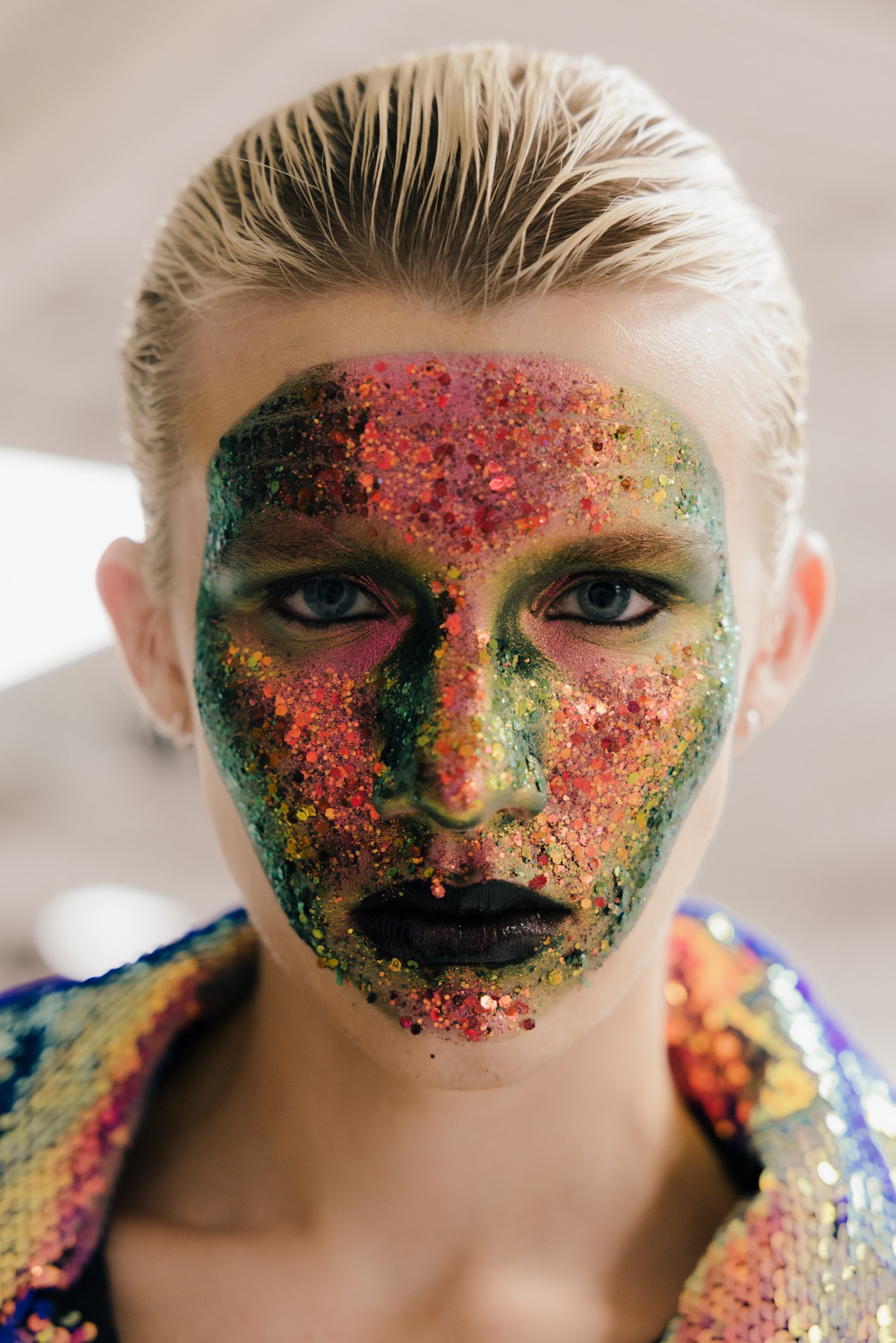 Vibrant face art with colorful glitter makeup for creative fashion style.