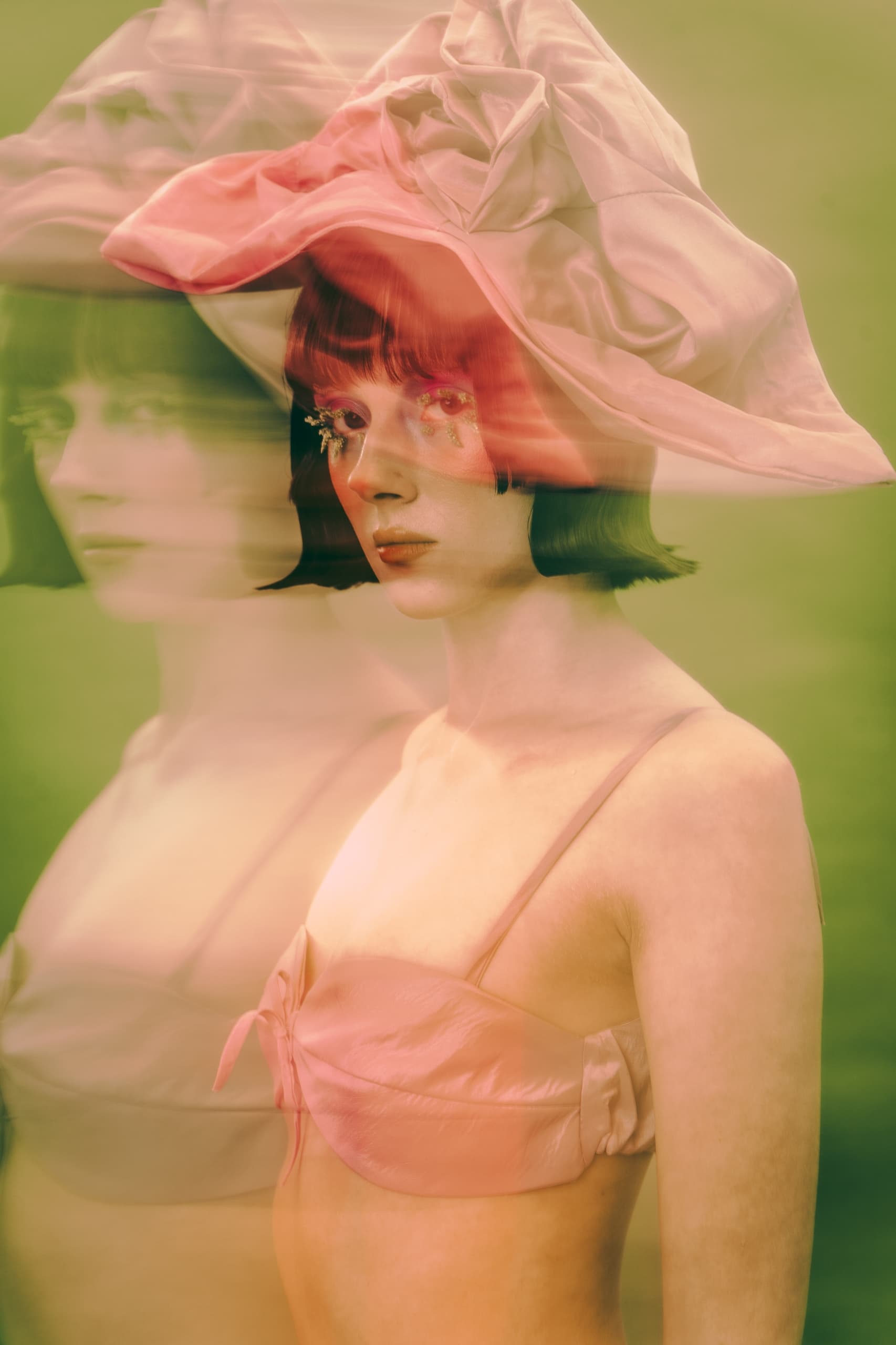 Artistic portrait of a woman in a pink hat with ethereal, blurred double exposure.