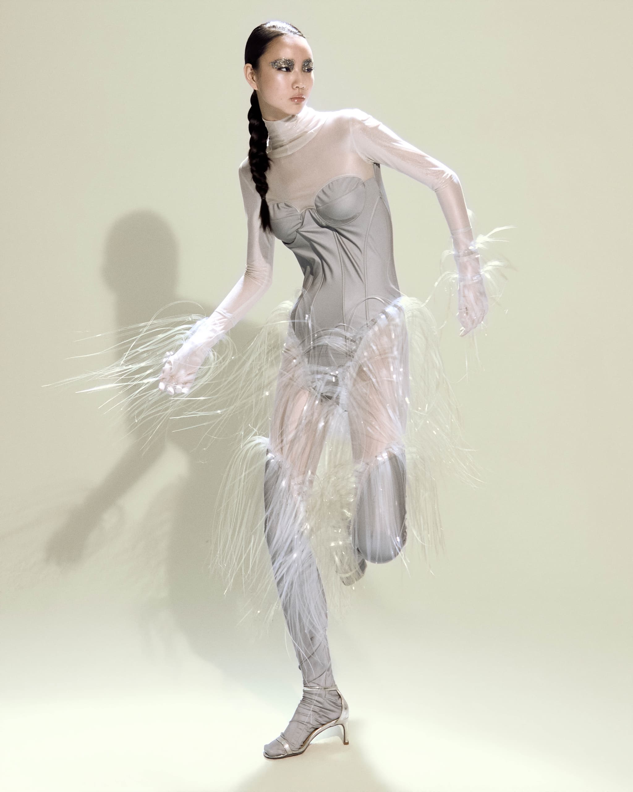 Futuristic fashion model in a striking avant-garde, feathery silver outfit.
