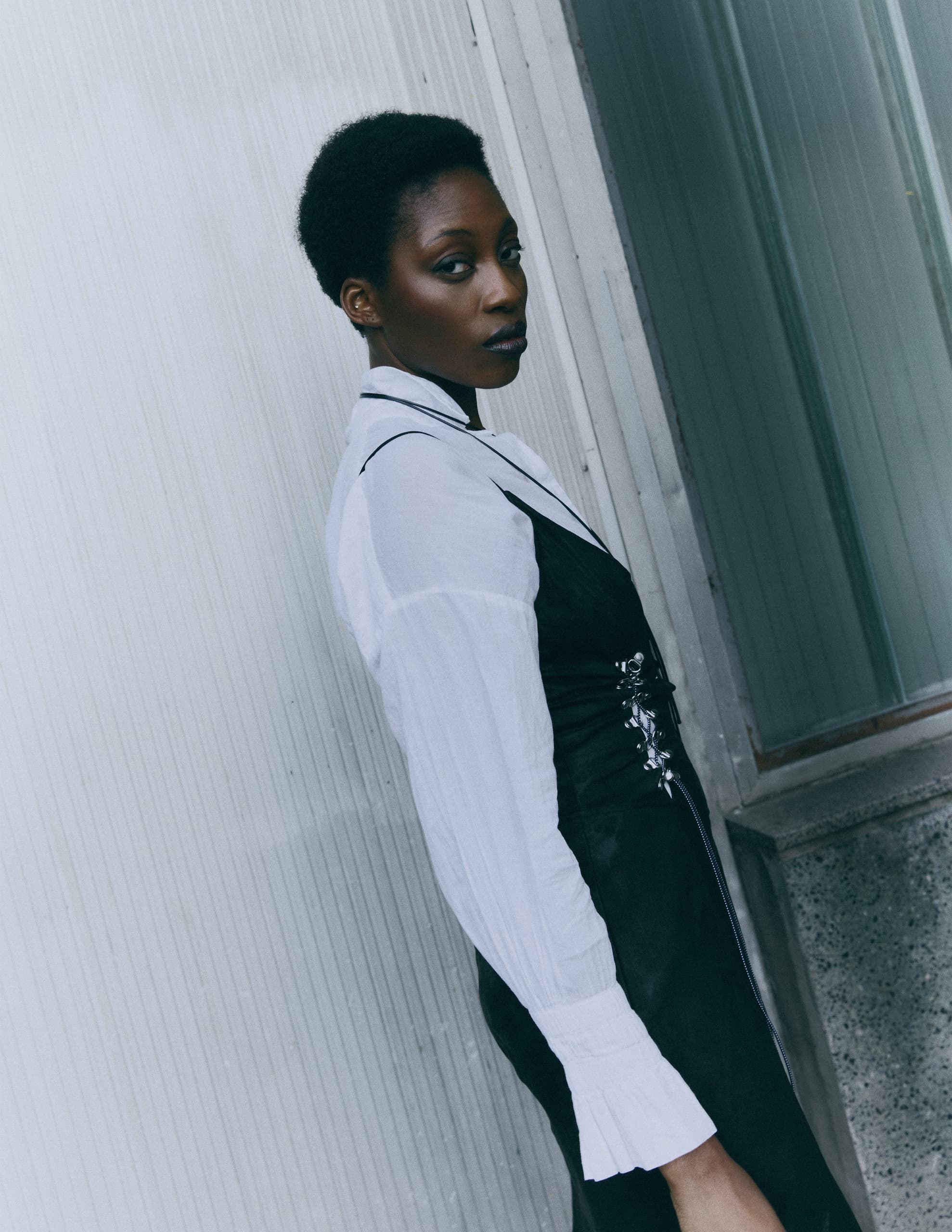 Stylish person in black and white outfit standing by a modern textured wall.