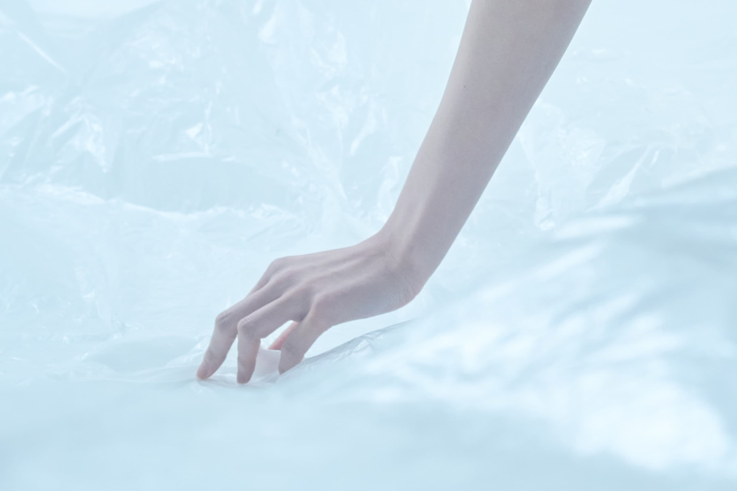 Hand touching translucent surface with soft light. Minimalistic and serene.
