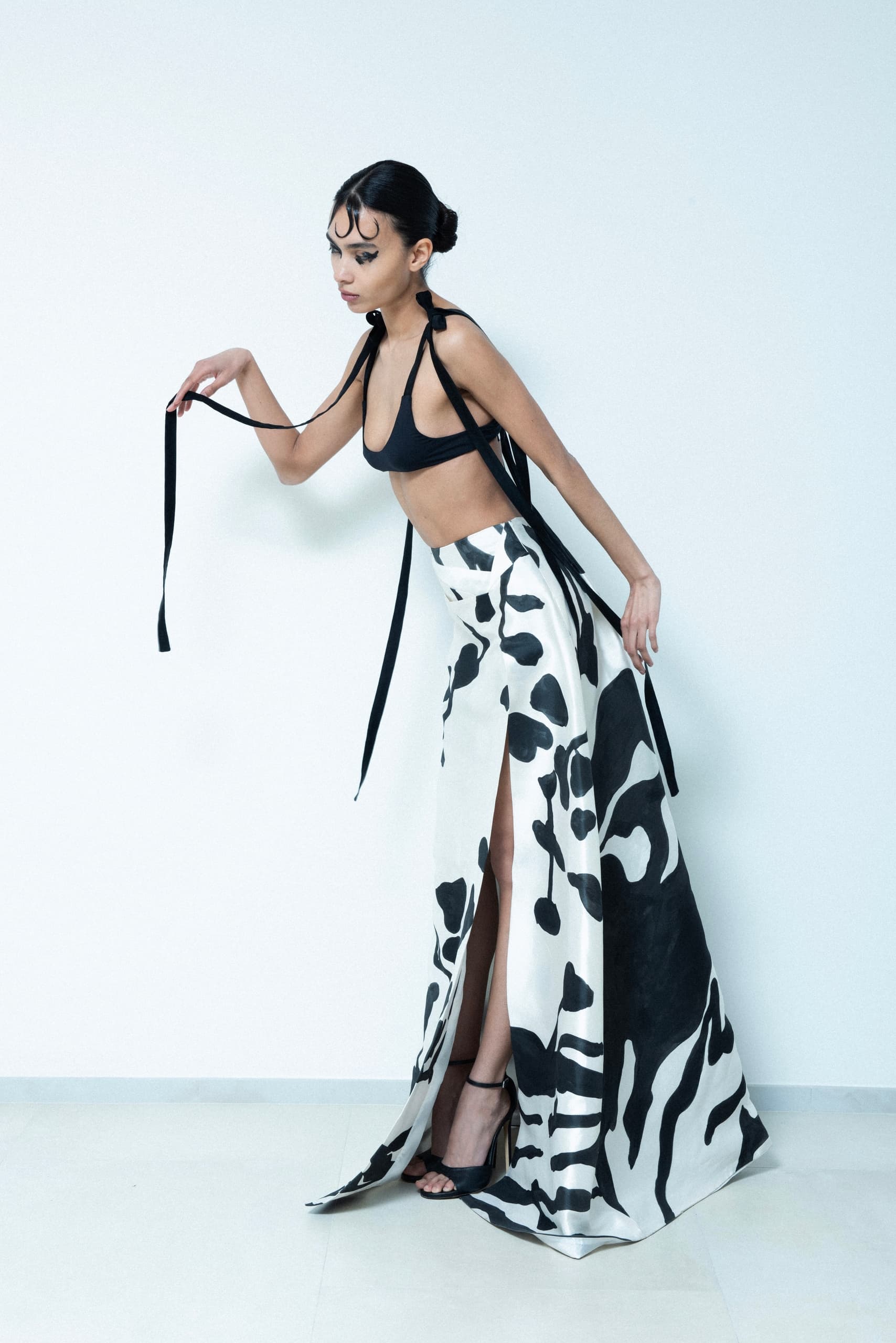 Fashion model in a chic black top and black-and-white patterned skirt.