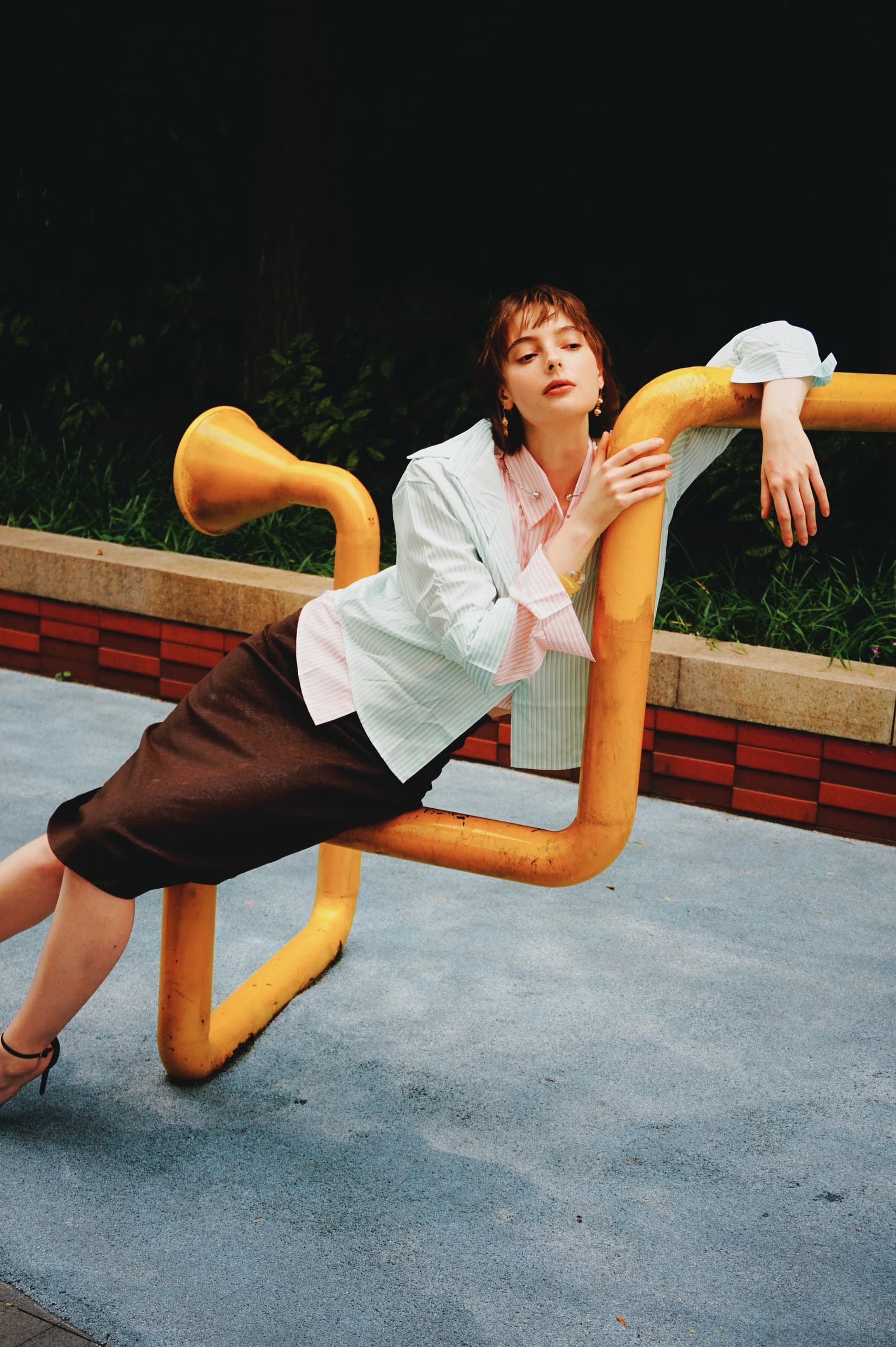 Fashionable person posing on unique yellow structure outdoors.