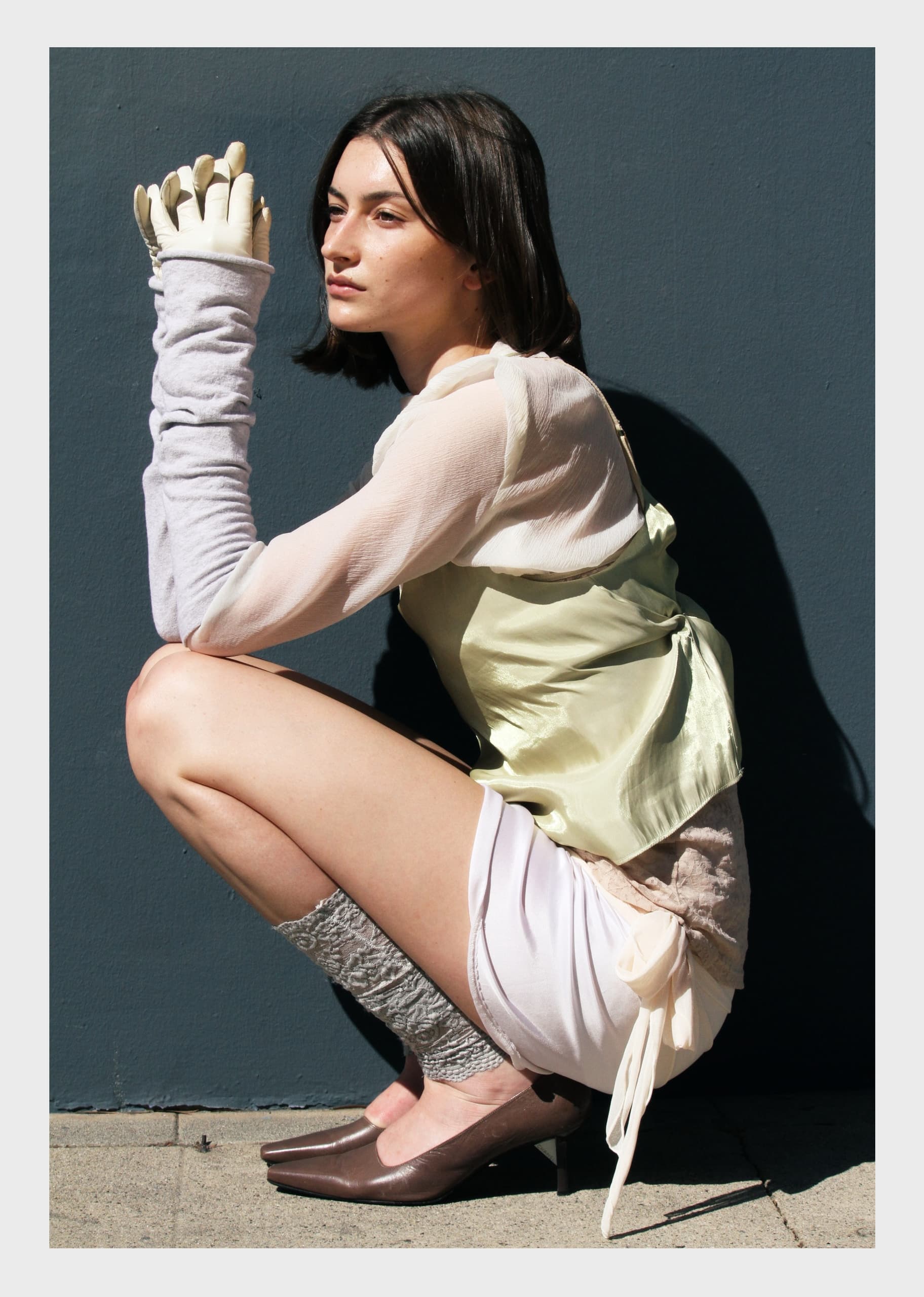 Fashionable woman in layered outfit and gloves in a creative pose.