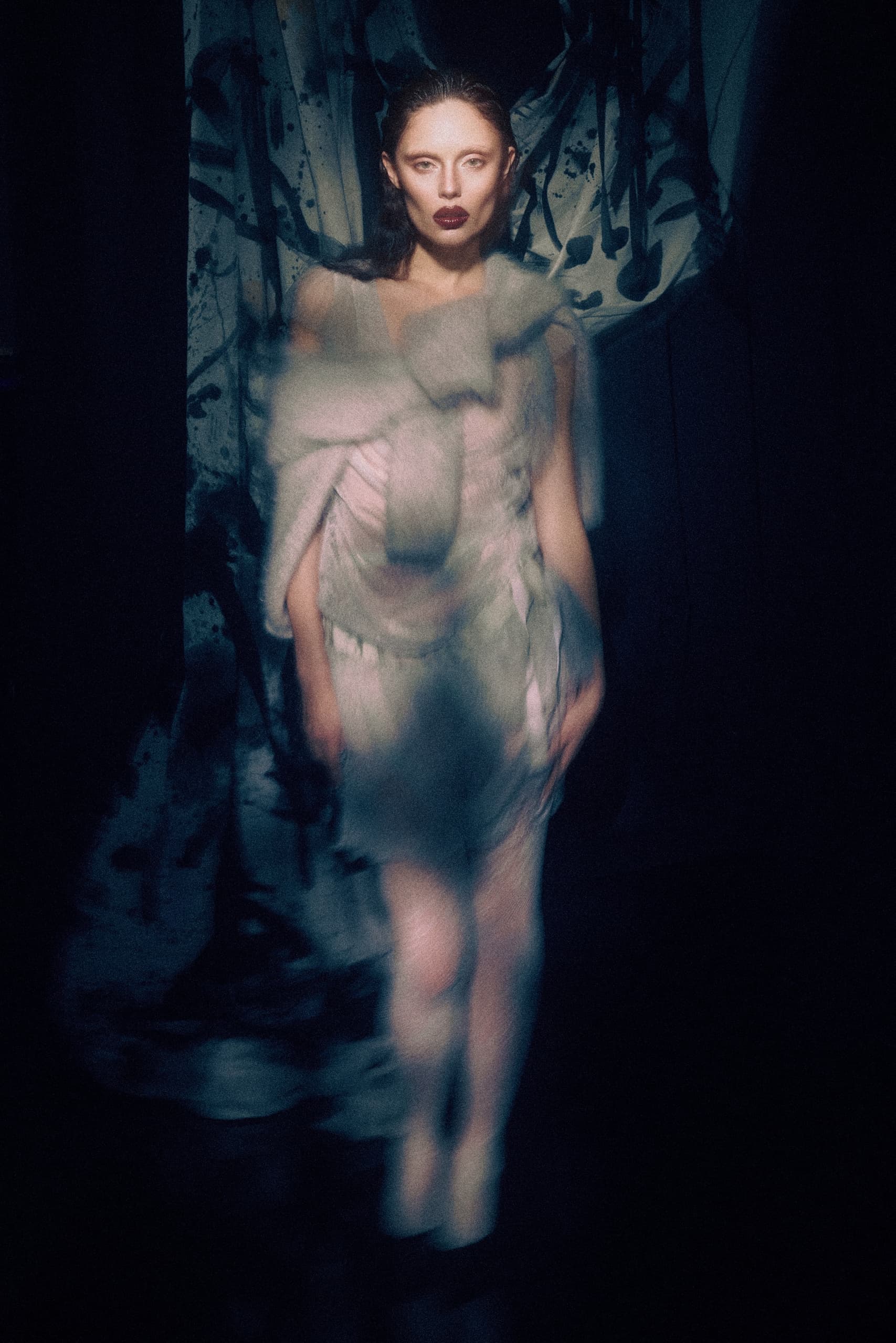 Mysterious fashion model in avant-garde outfit with dramatic lighting.