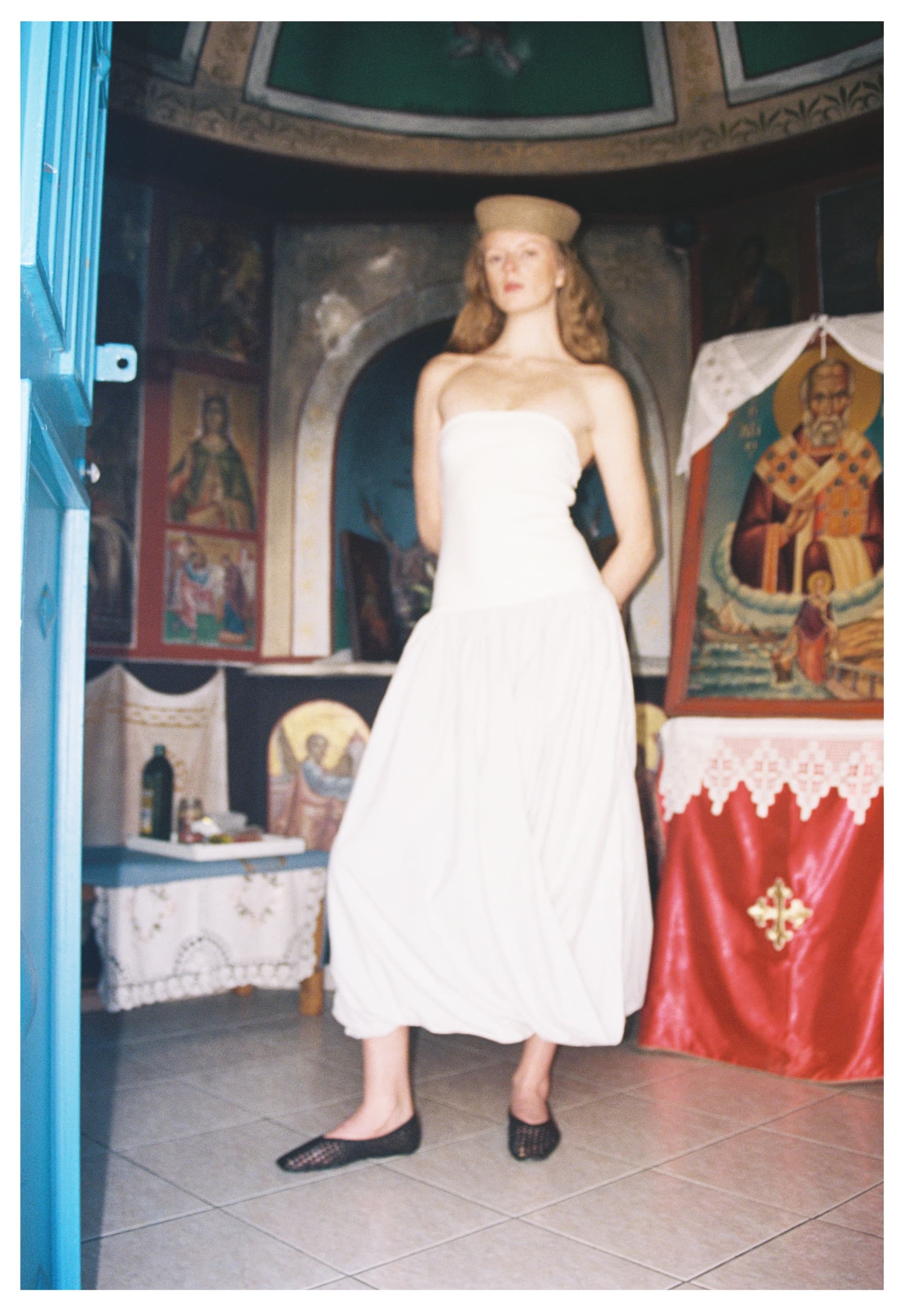 Person in white dress and hat inside a decorated room.