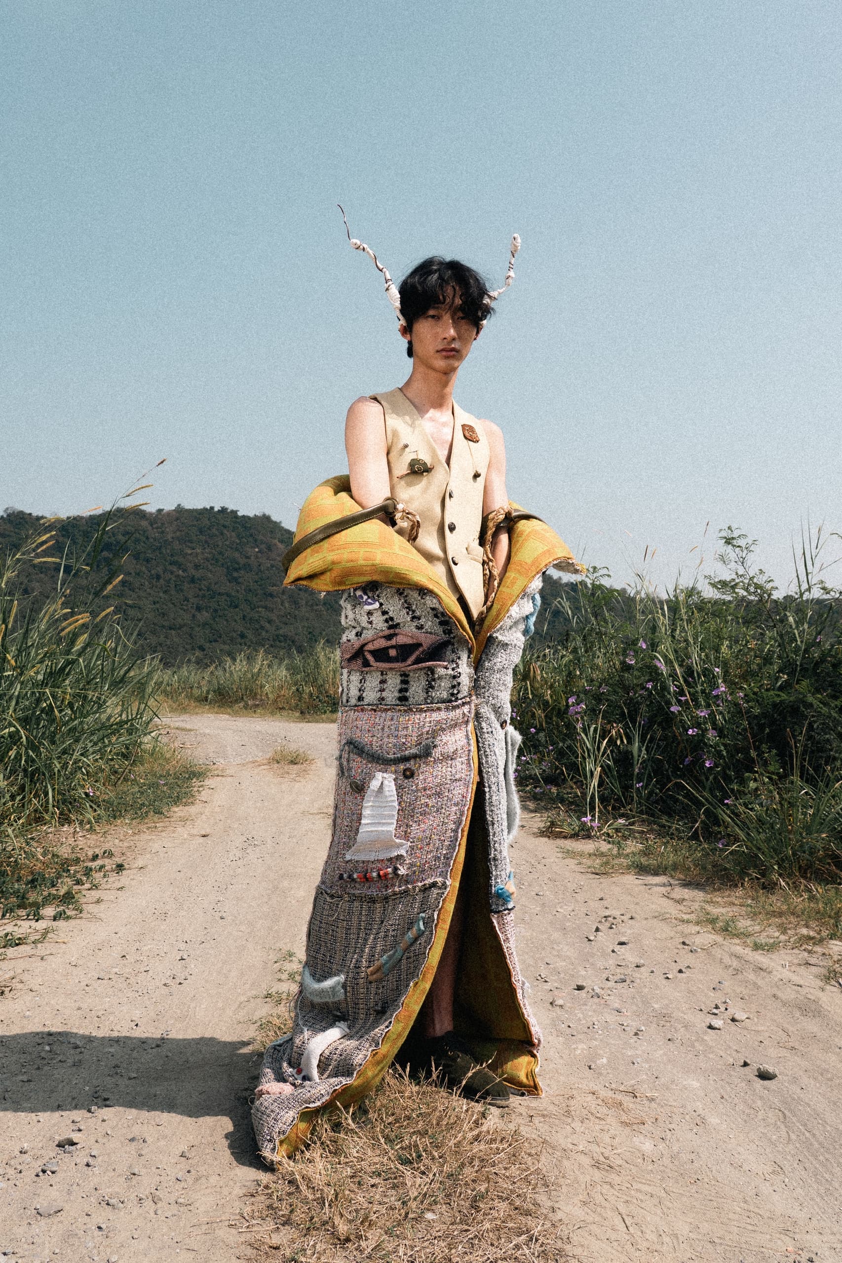 Person wearing unique avant-garde fashion on a rural path.