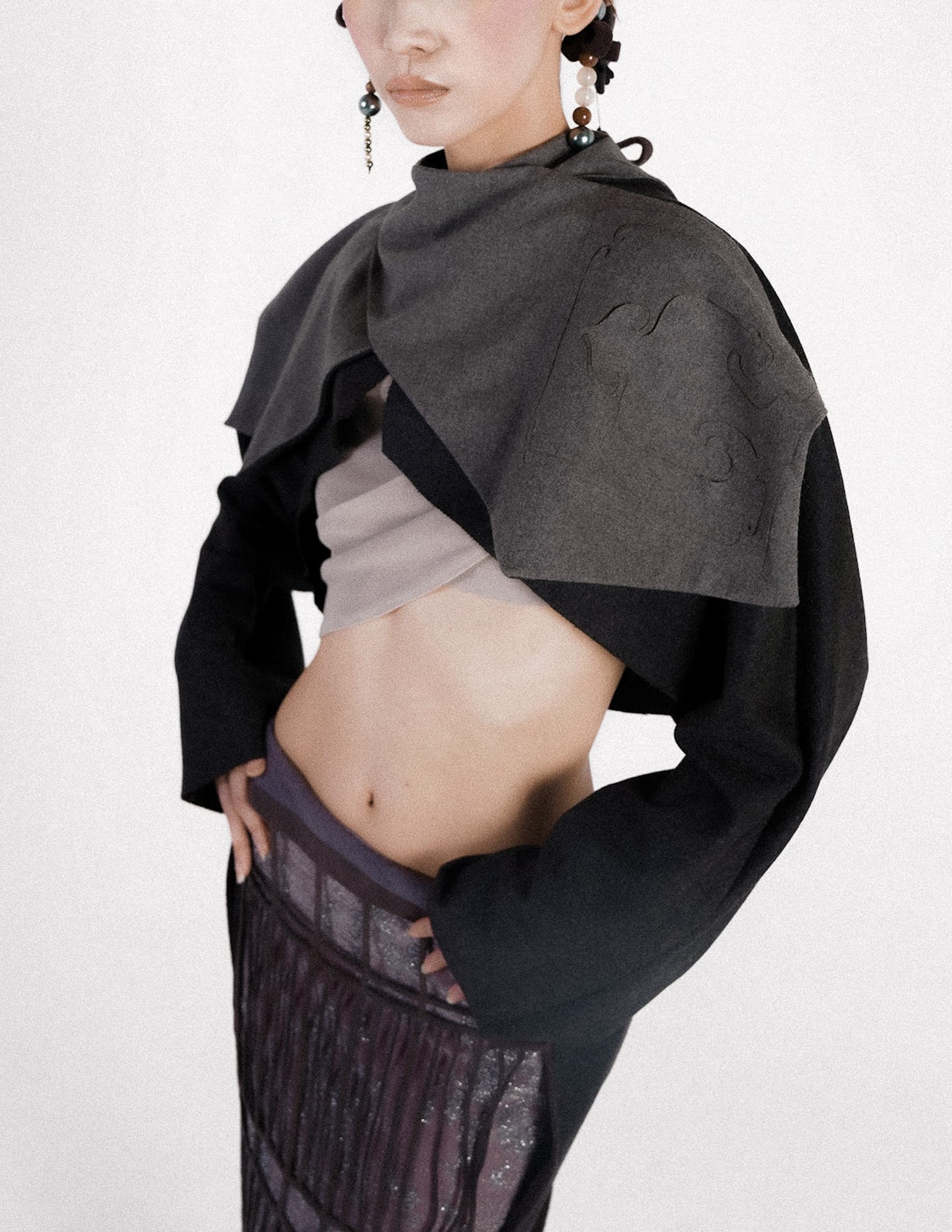 Fashionable woman in modern layered outfit and statement earrings.