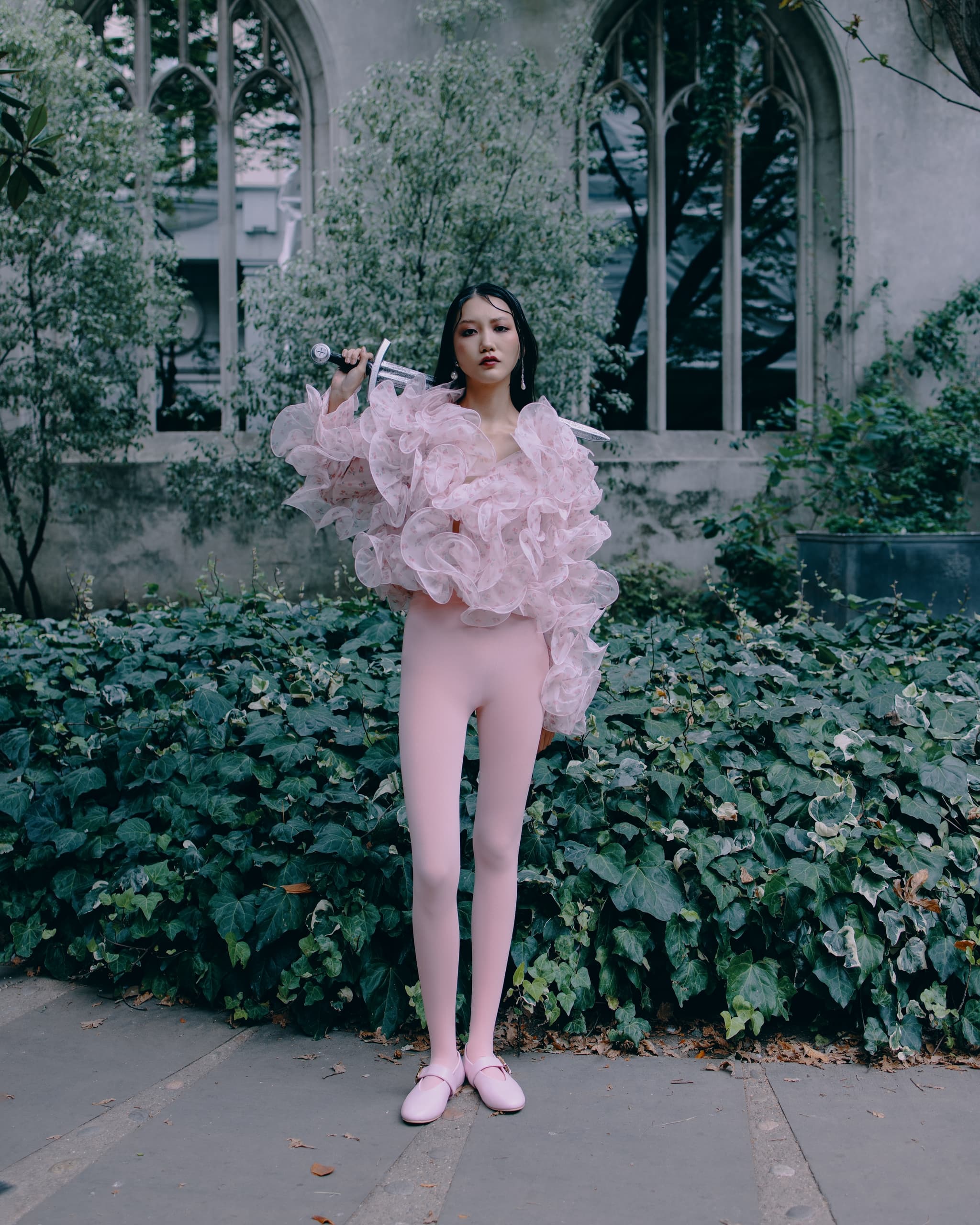 Person in pink outfit holding a sword in a lush garden setting.