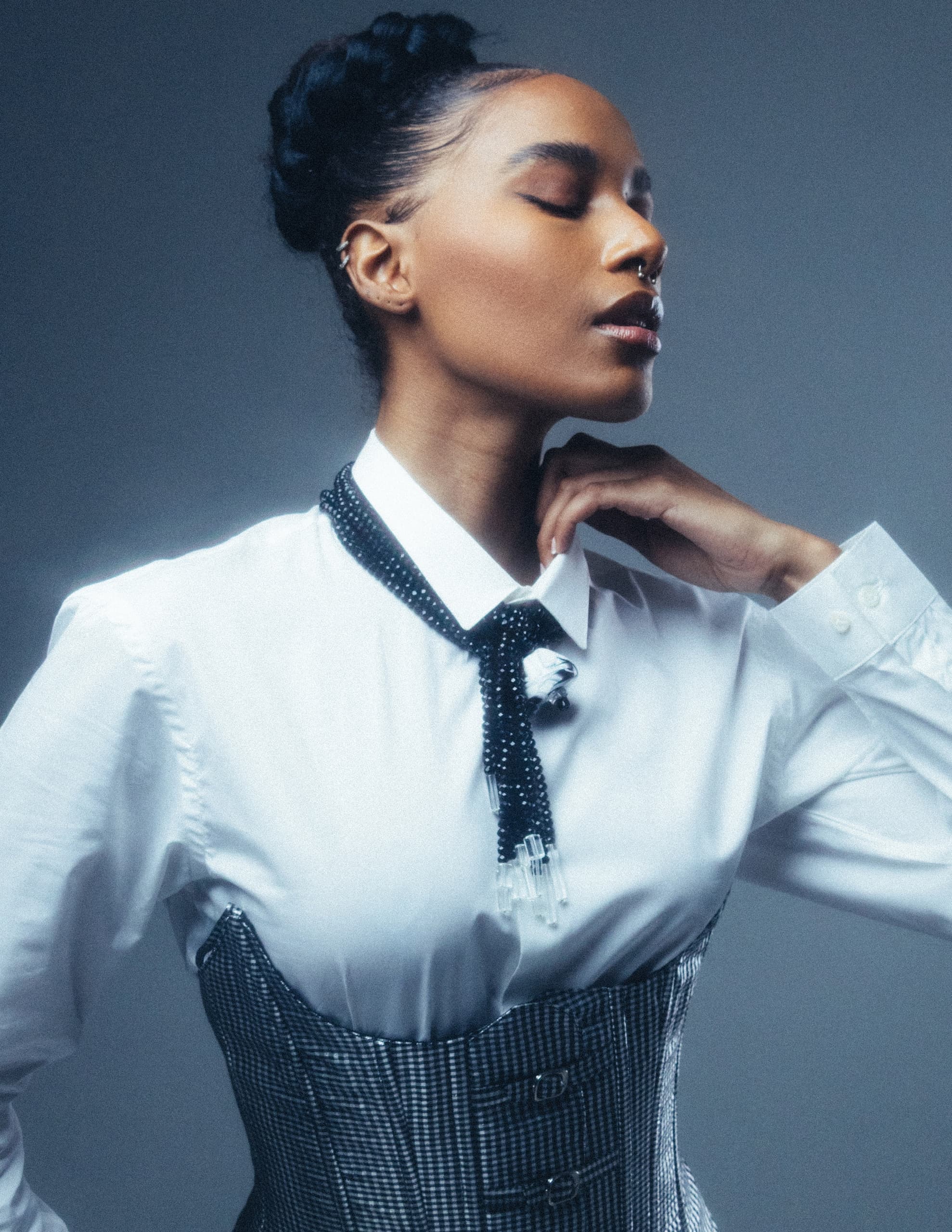 Fashionable woman in chic corset and blouse posing with elegance.