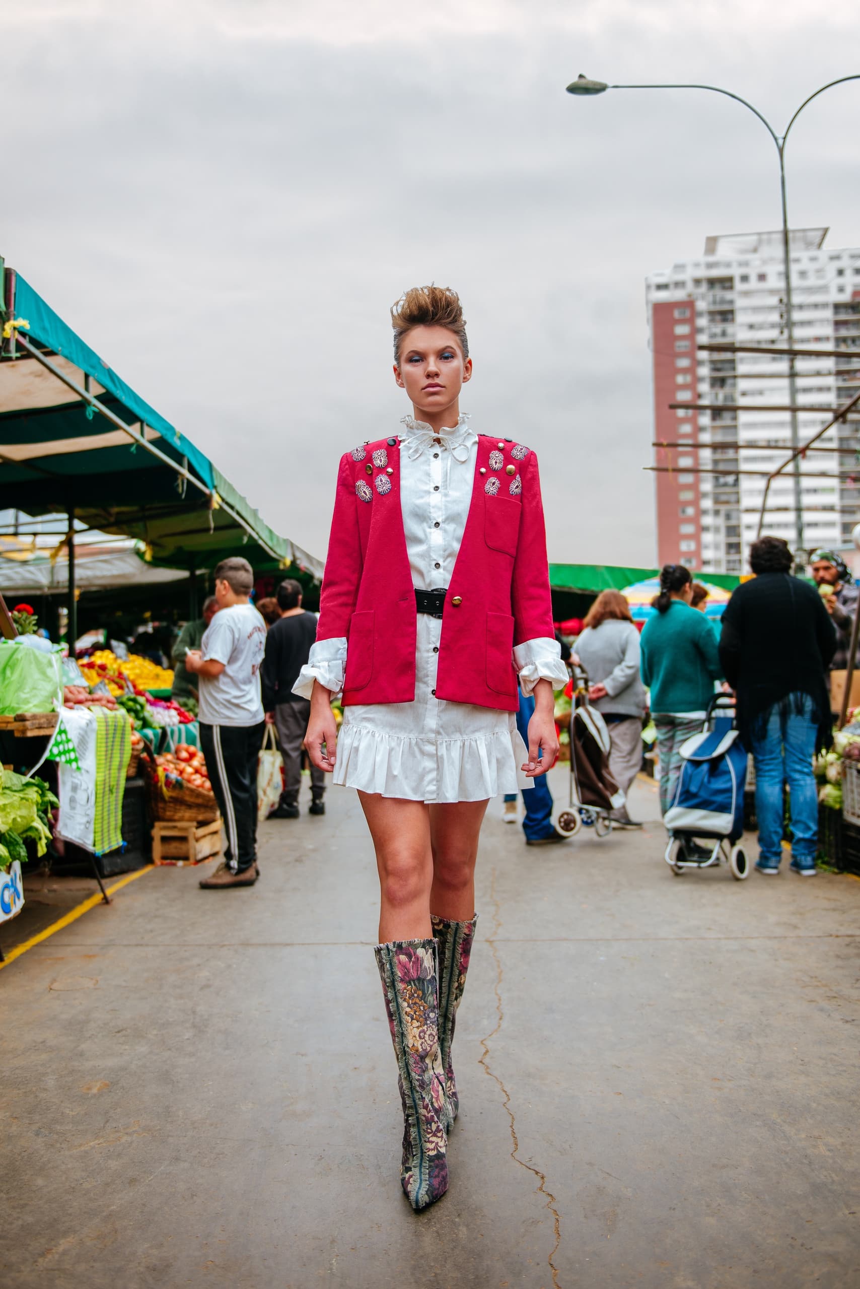 Fashionable woman in chic outfit walking through a vibrant street market.