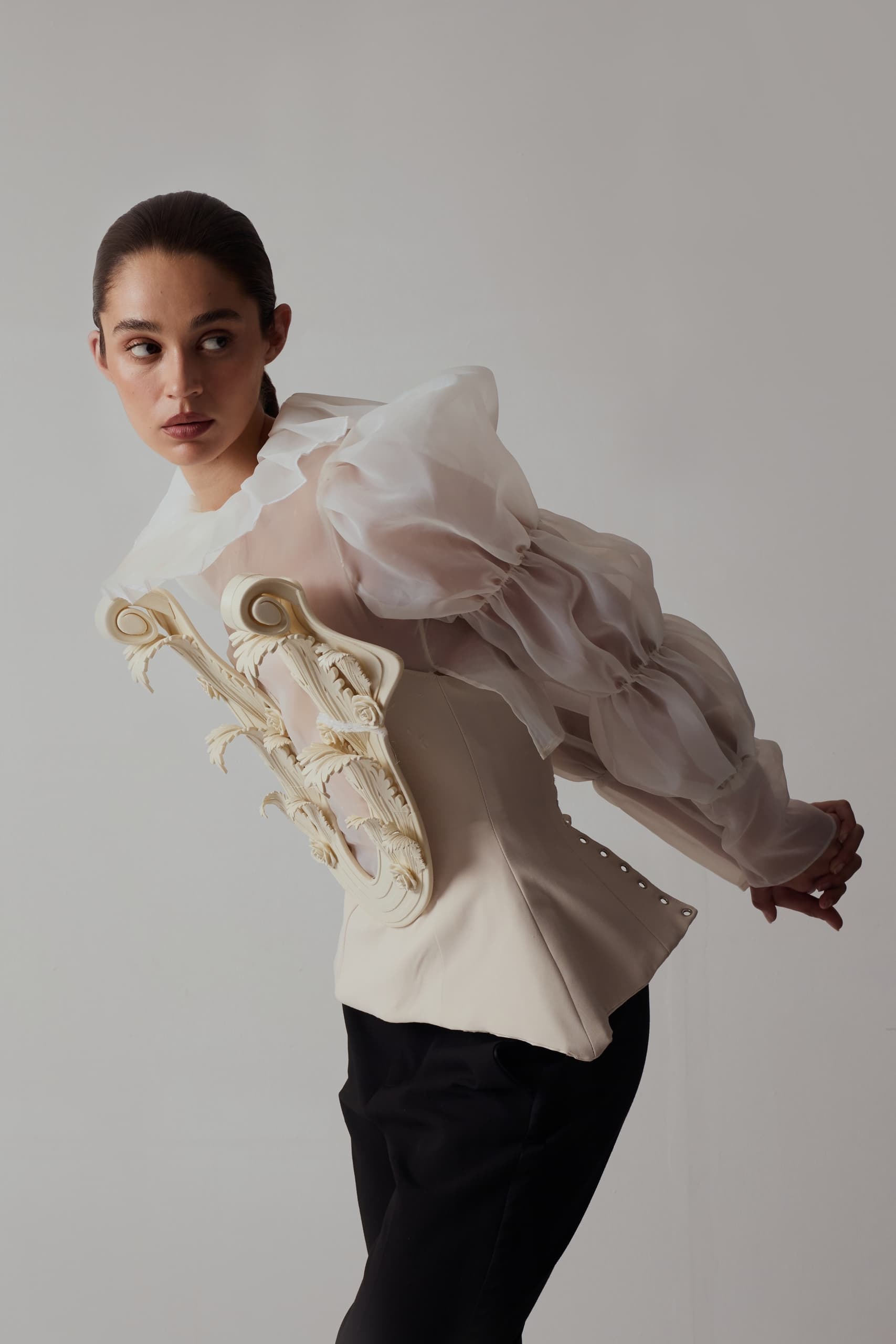 Fashion model in artistic white blouse with sheer sleeves and decorative back detail.